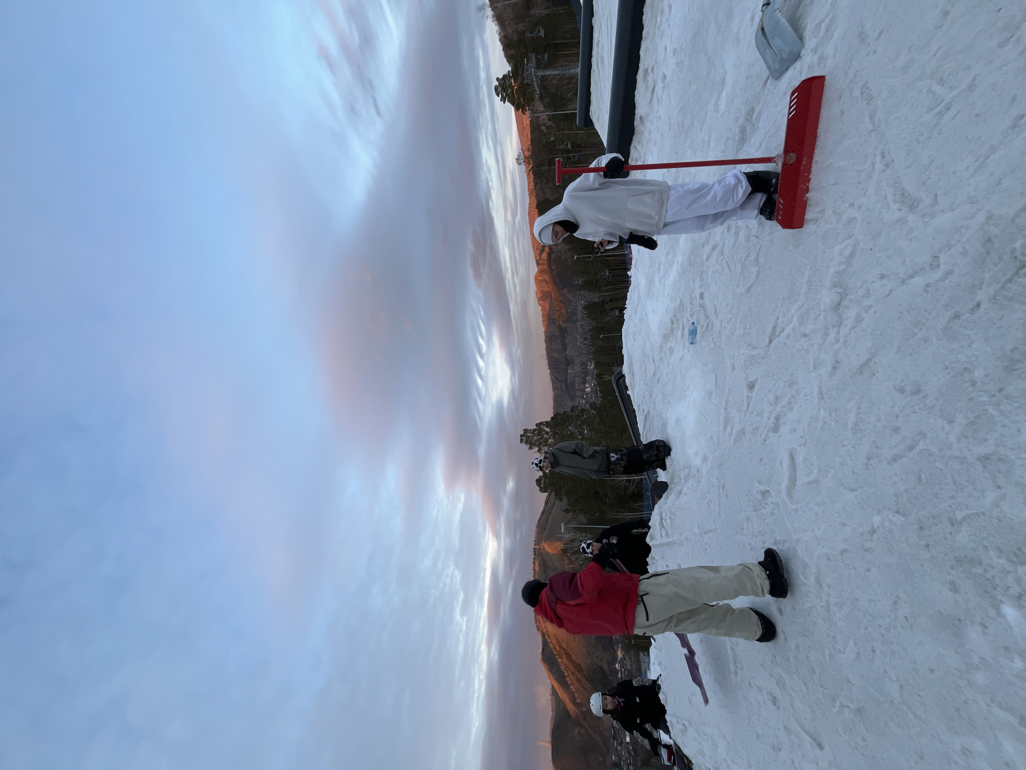 Snow maintenance worker clears slopes as skiers gather at mountain resort