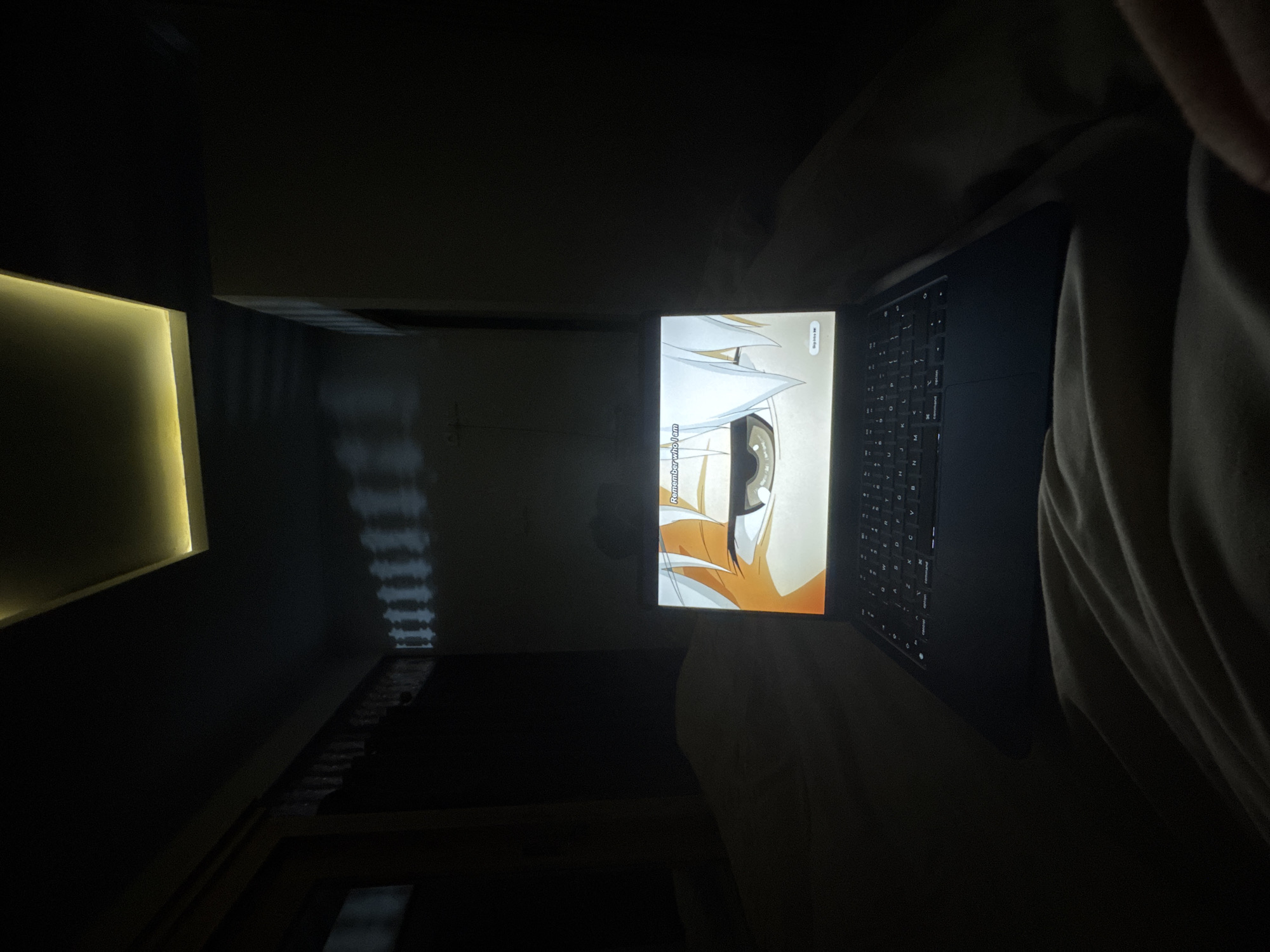 Person watches anime on laptop in dark room