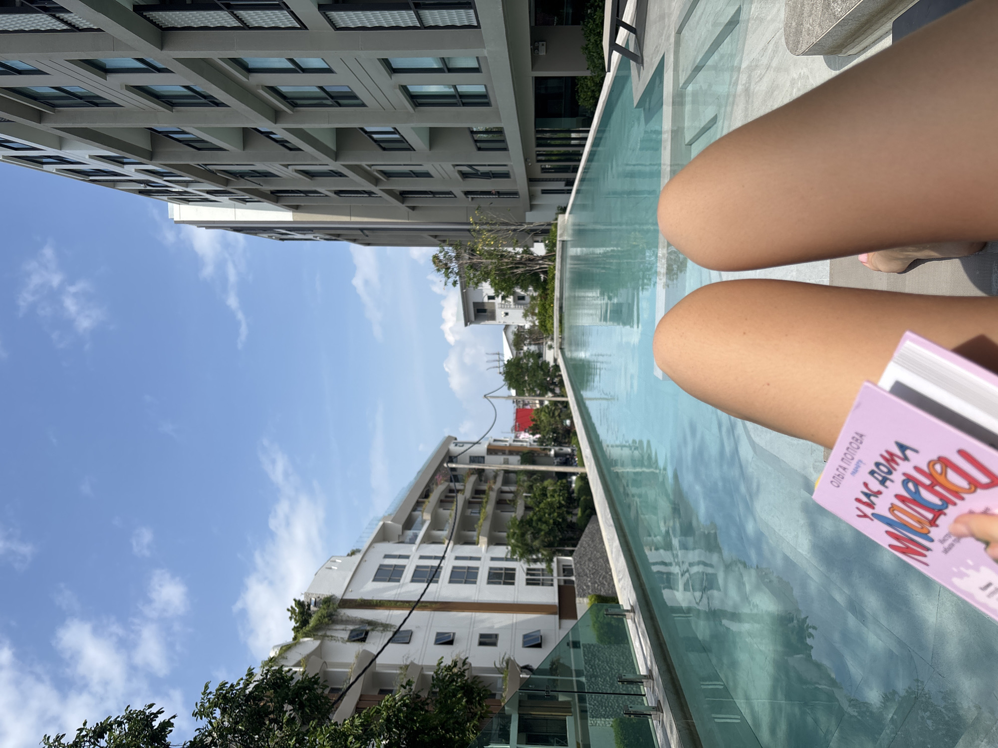 Person reads pink book poolside in Choeng Thale, Thailand