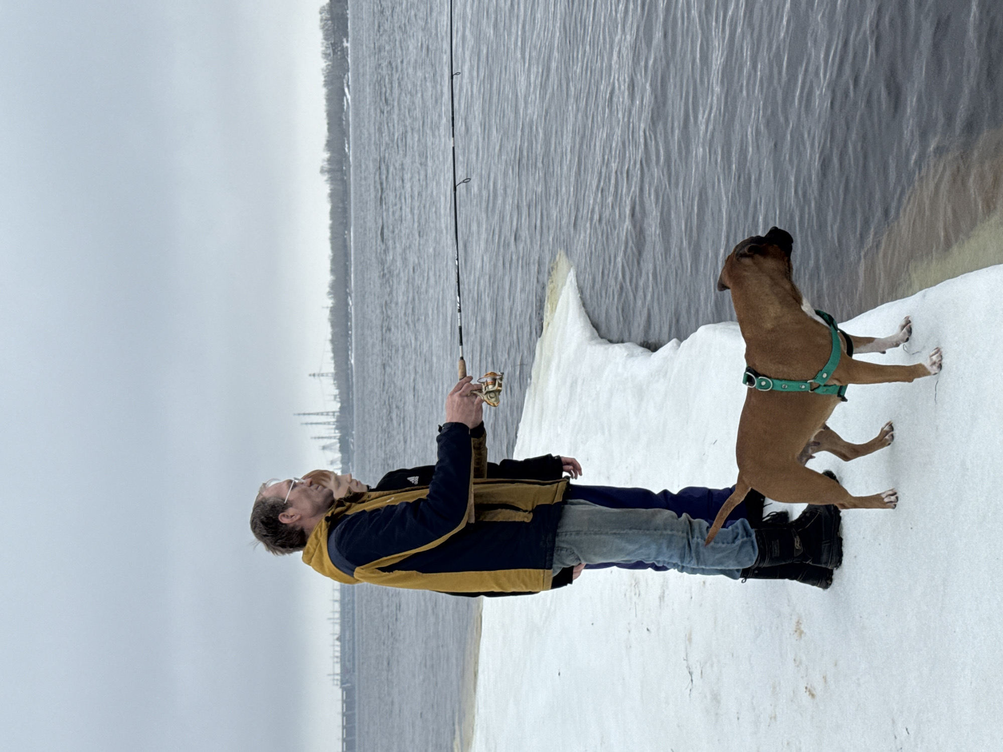 Family fishing trip with playful dog on frozen Russian reservoir