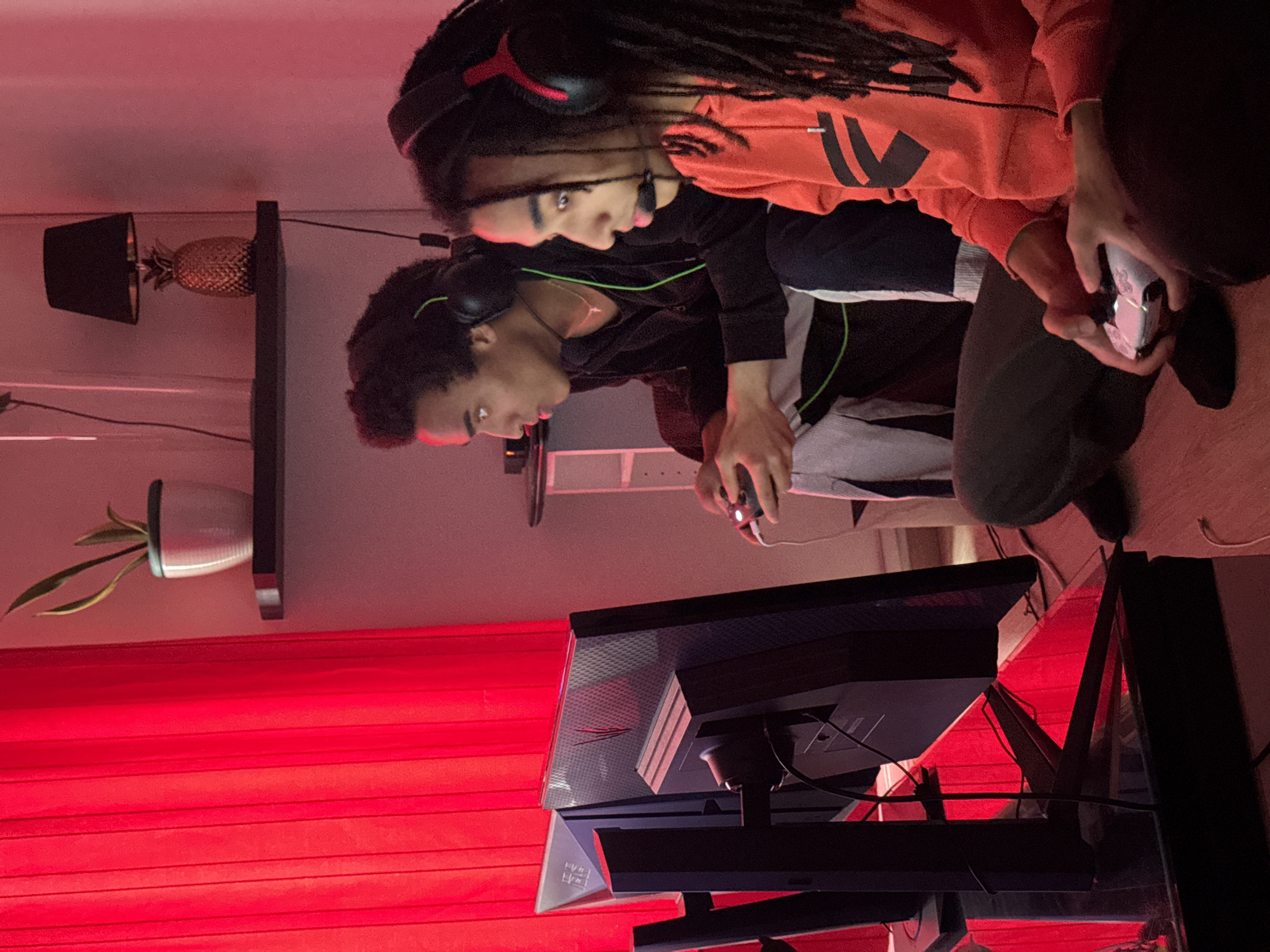 Two friends gaming together in red-lit Paris apartment