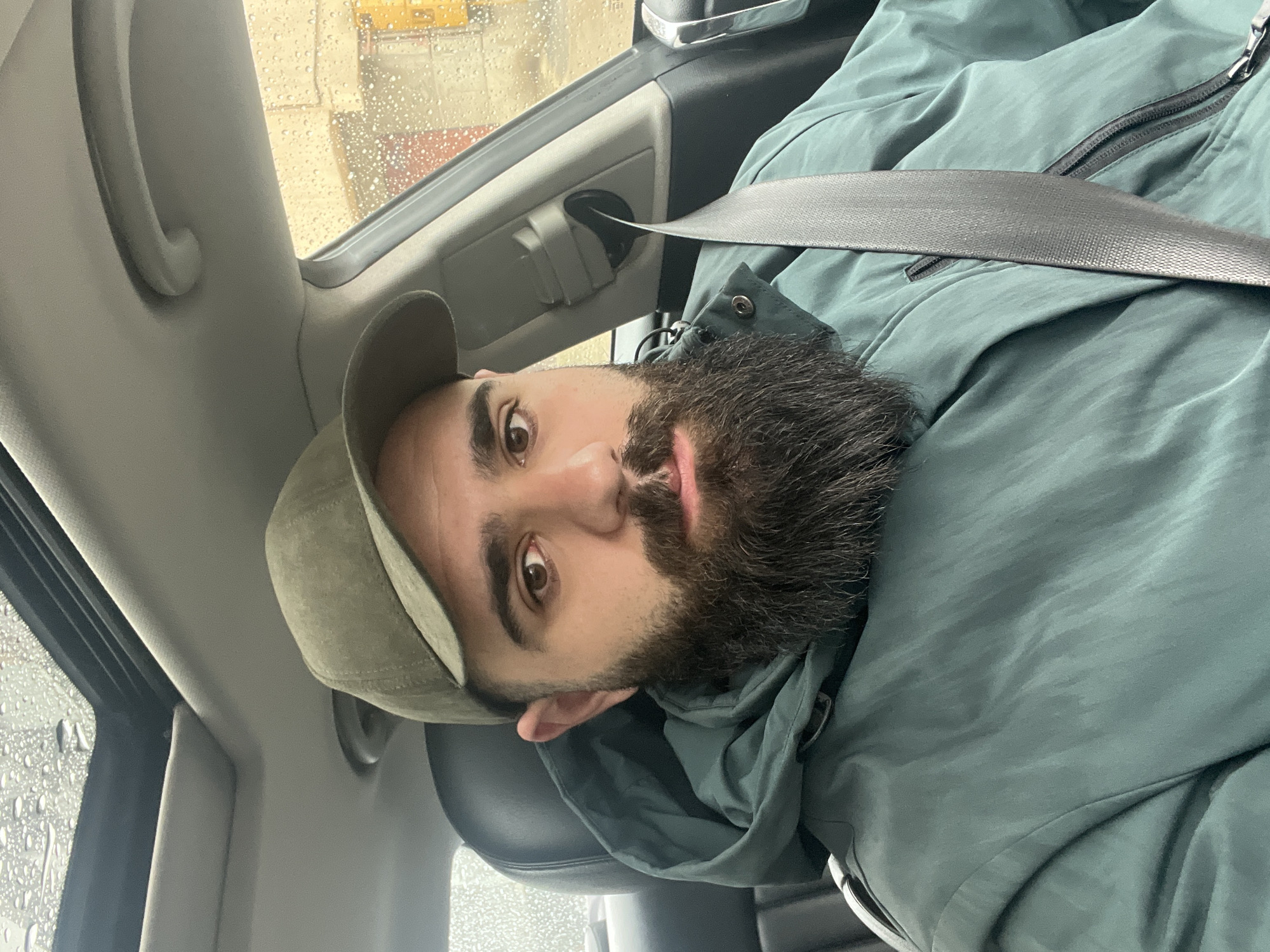 Man in green jacket sits in car during rain in Dobrich