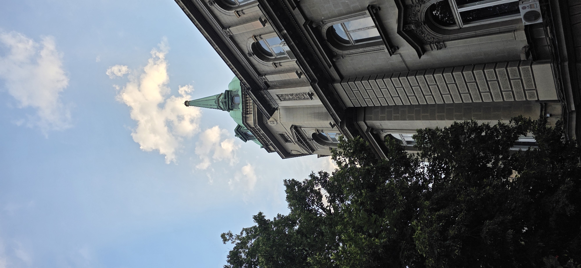 Historic stone building facade alongside a lush tree in Belgrade