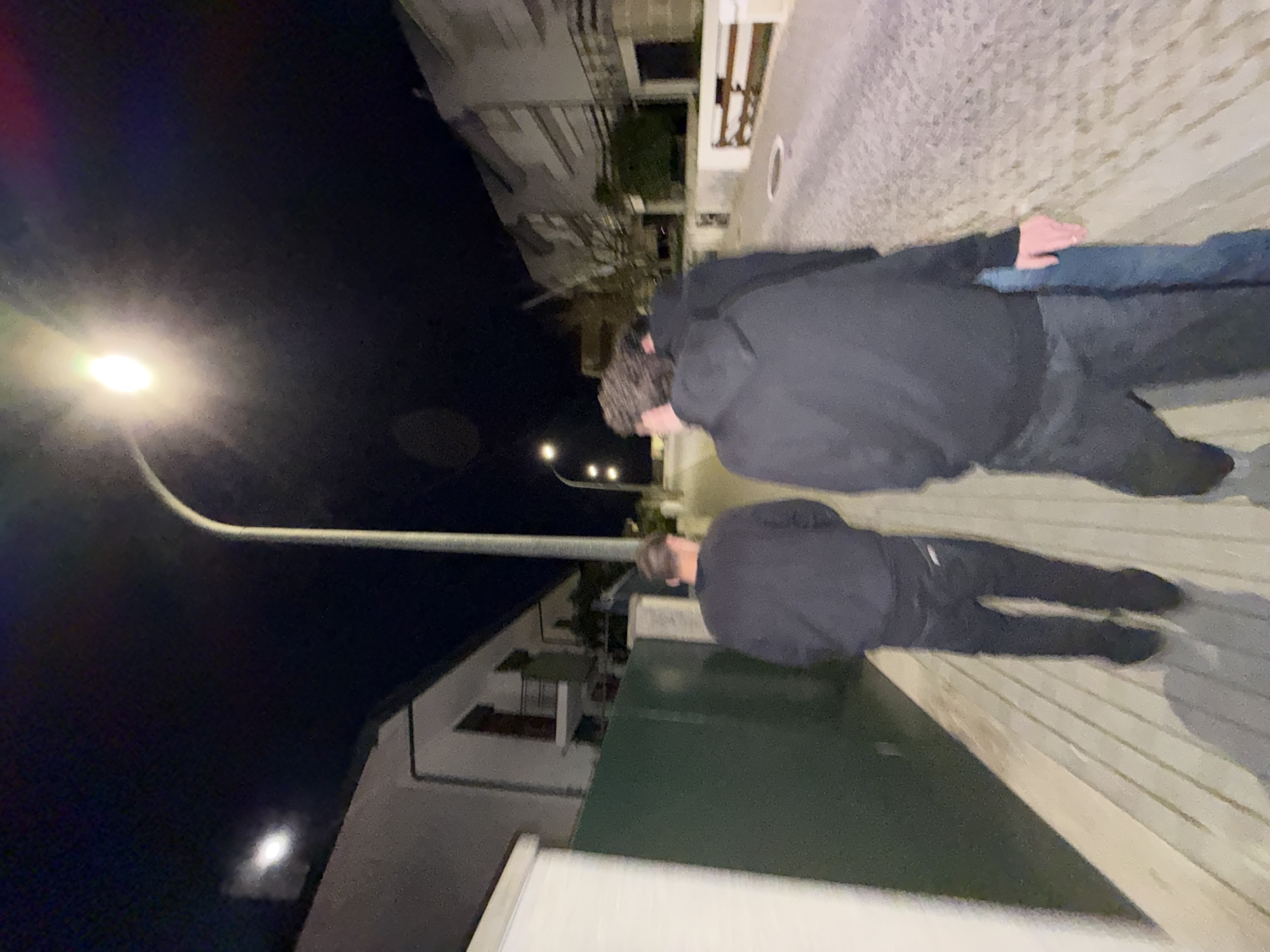 Two people walk illuminated street in Vila Real at night