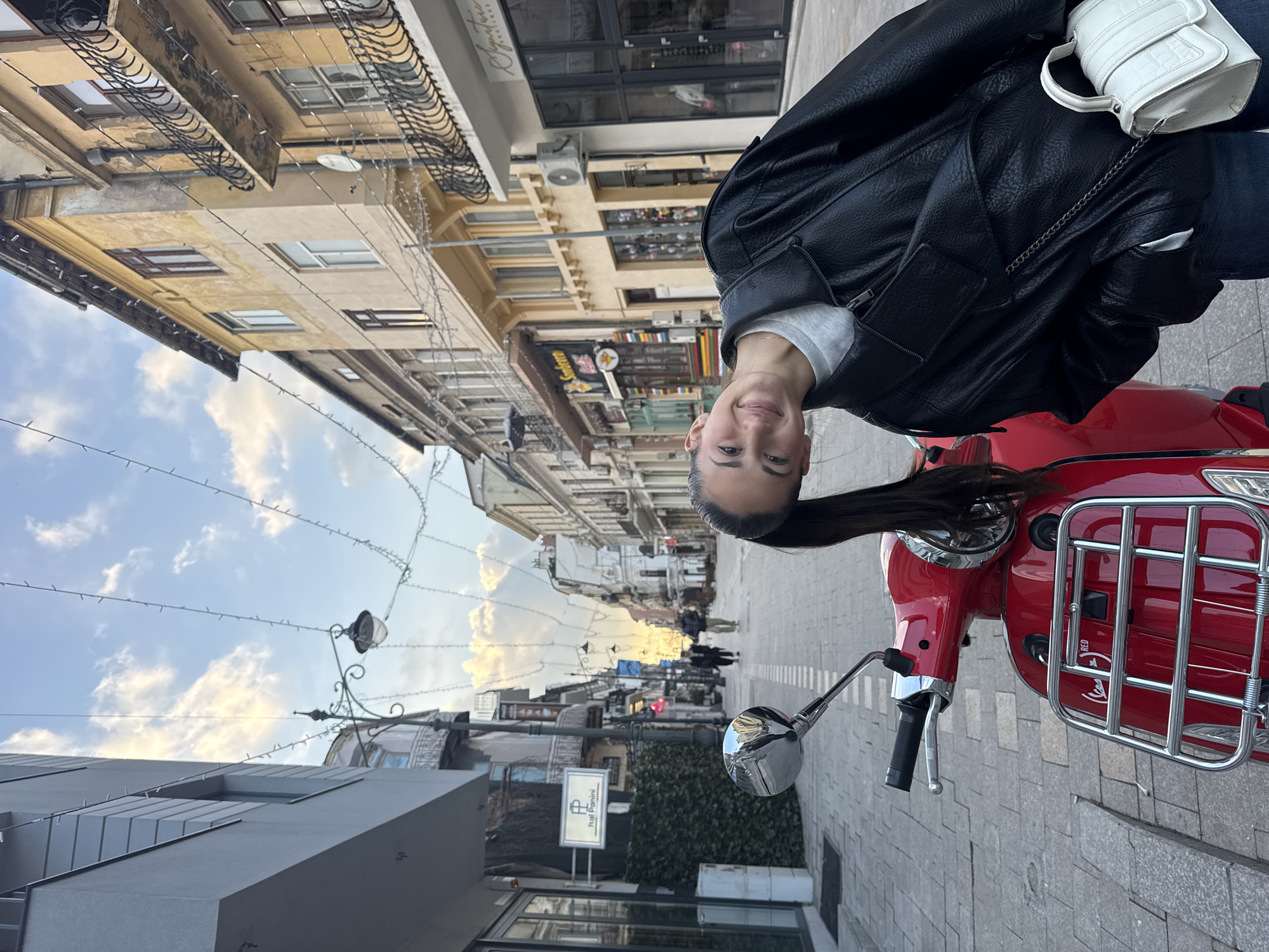 Woman poses with red scooter near Romanian museum