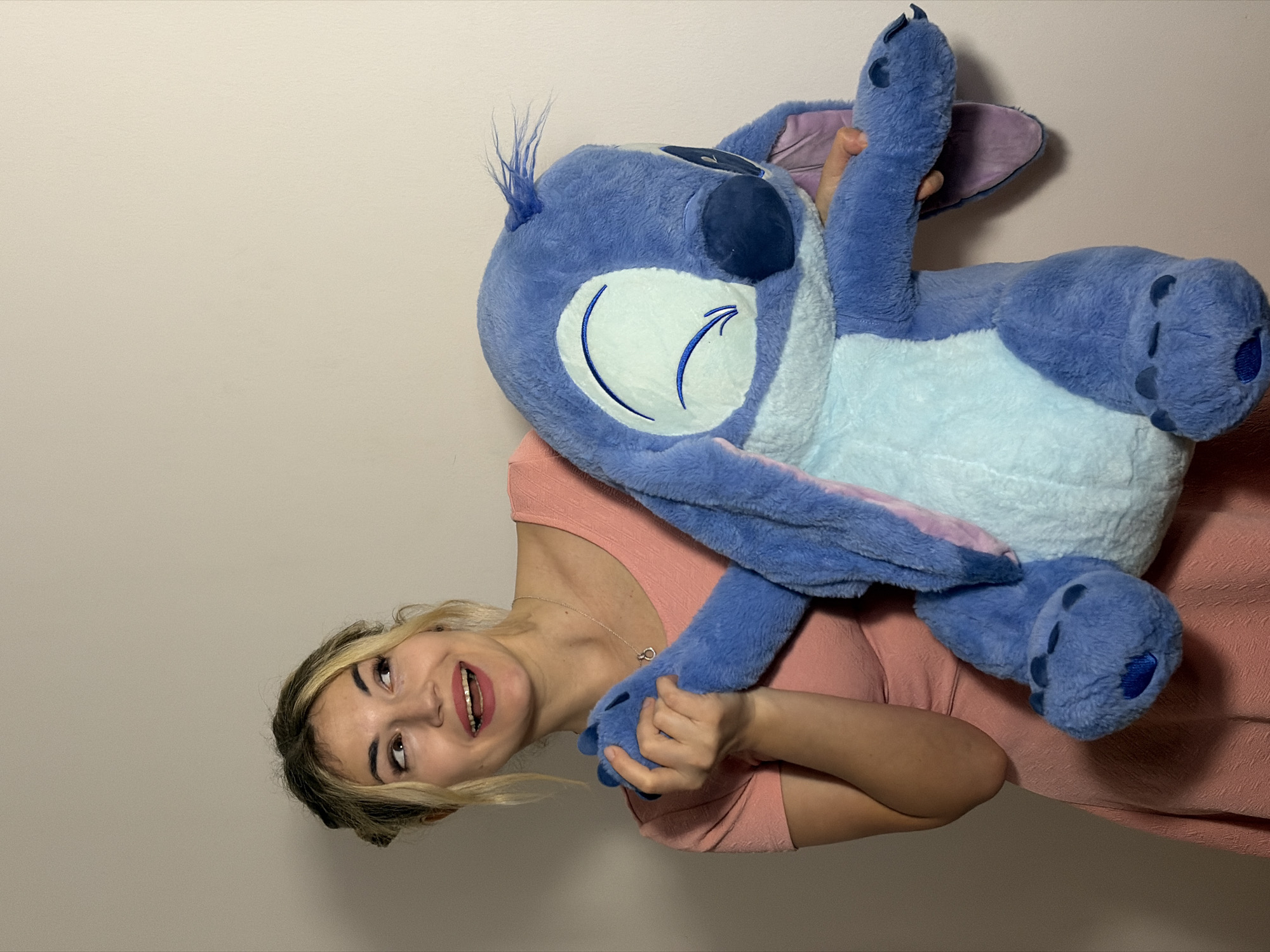 Woman playfully poses with Disney Stitch plush toy in Budva