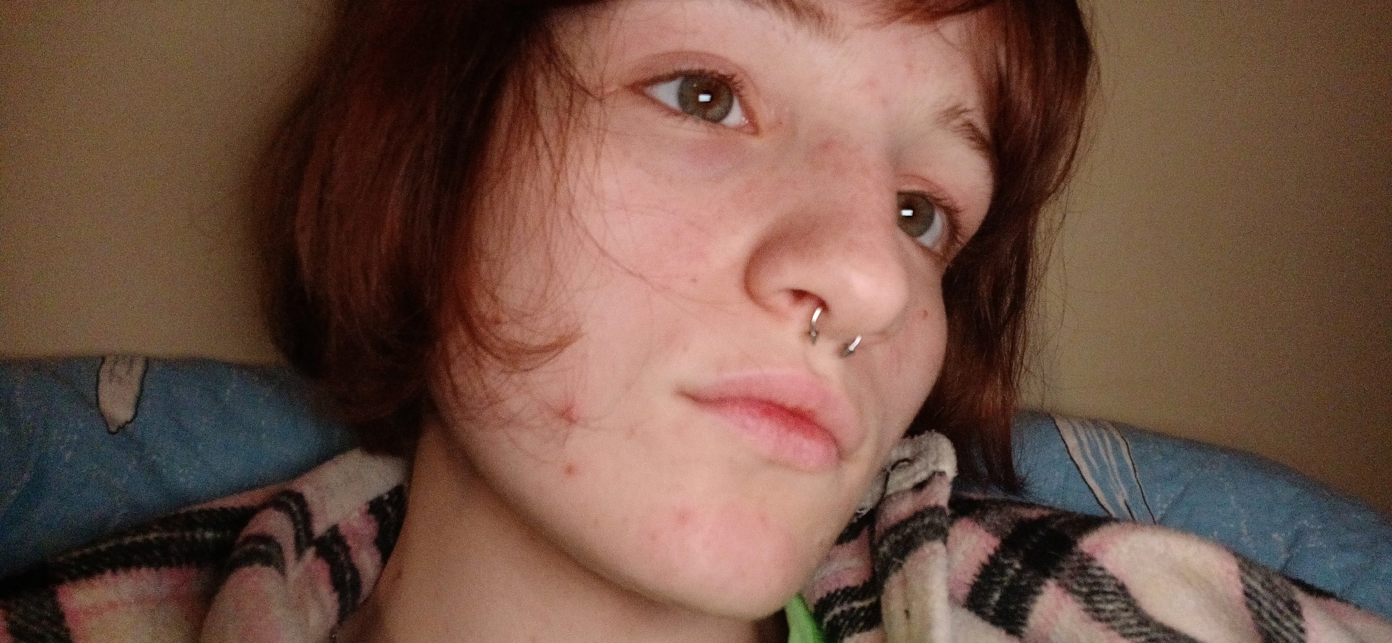Person photographed in intimate close-up with plaid blanket