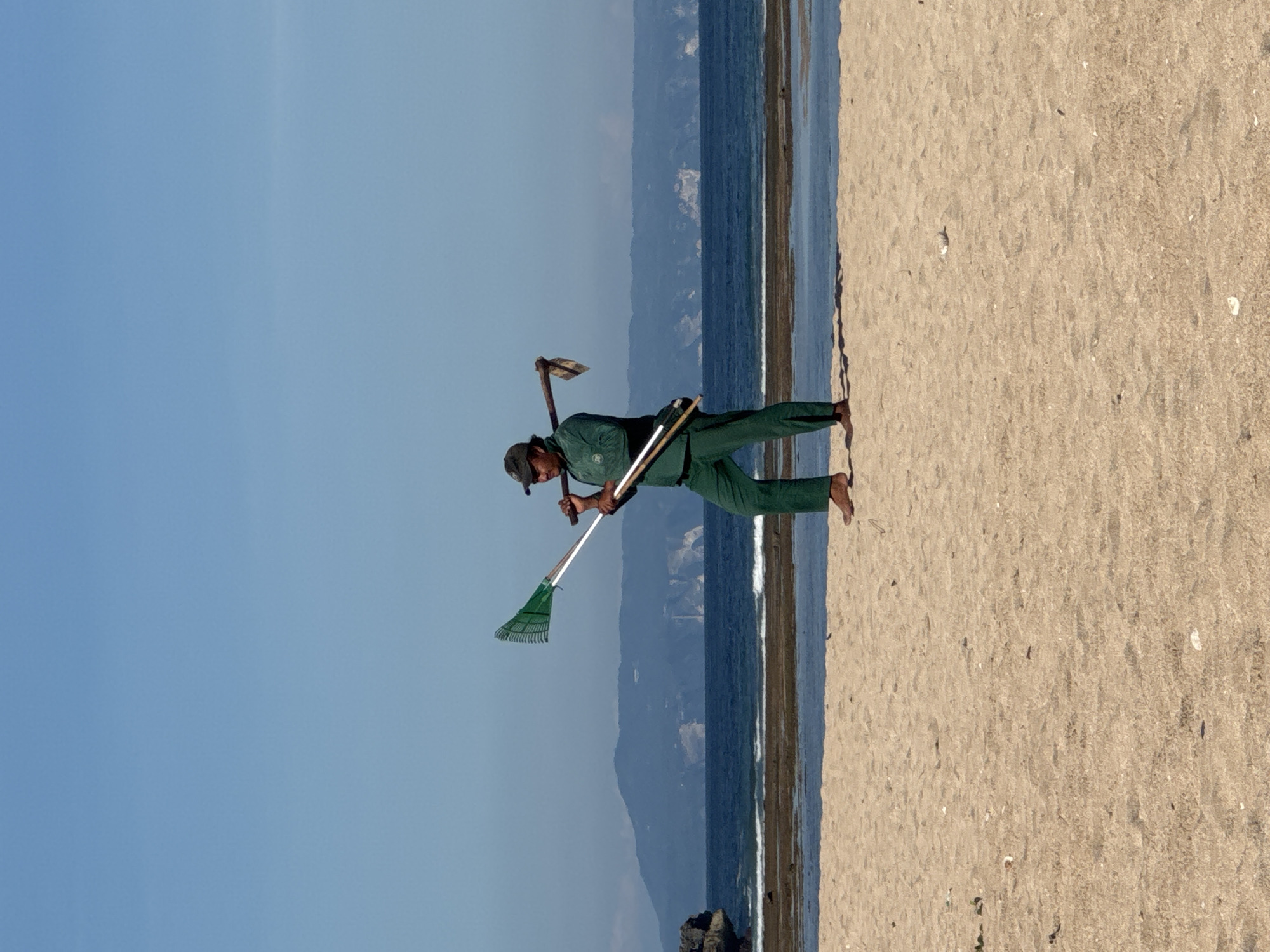 Beach cleanup worker and children spotted on Kuta Selatan shore