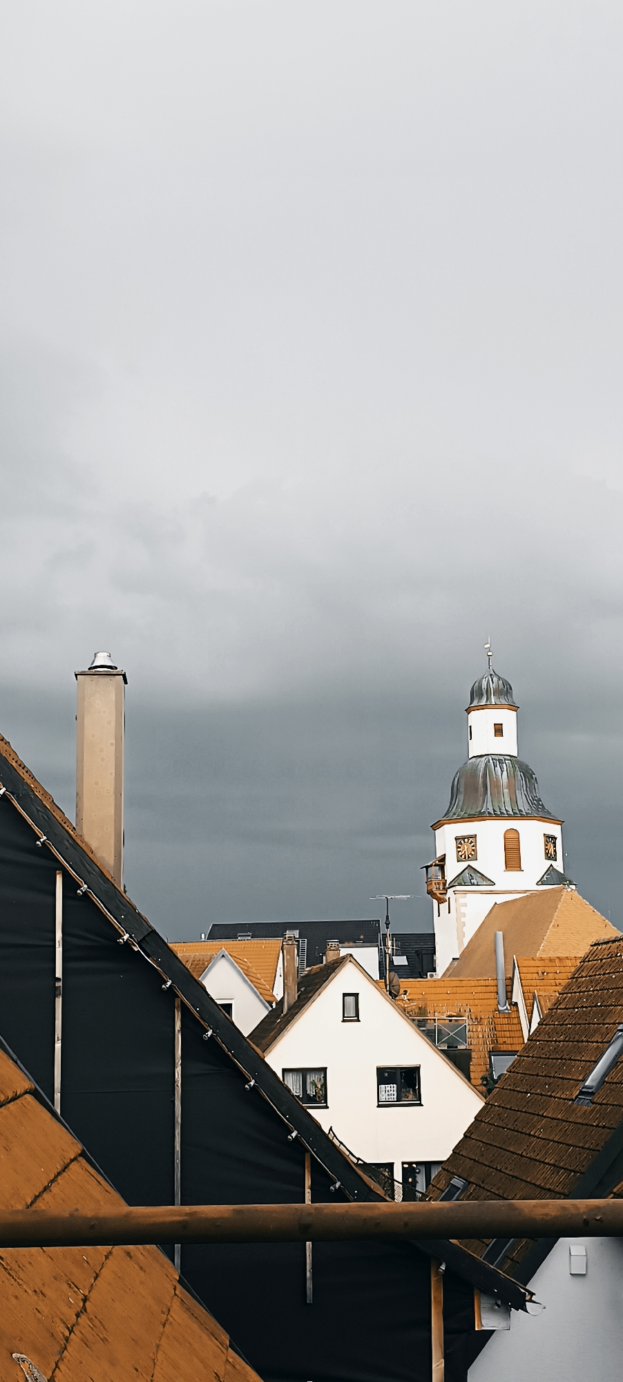 Pigeons on railings above Winnenden rooftops, storm clouds rolling in