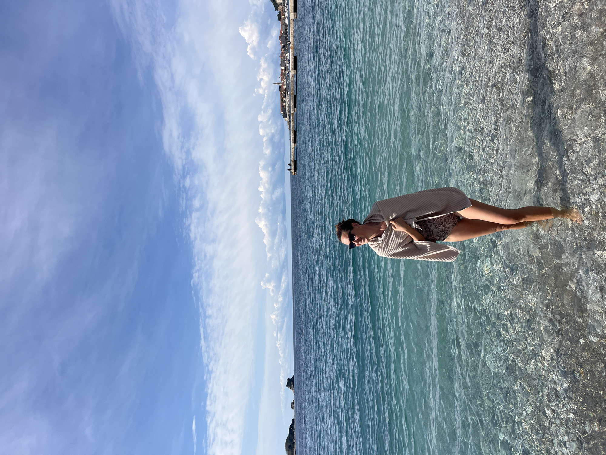 Woman stands in clear coastal waters in Budva