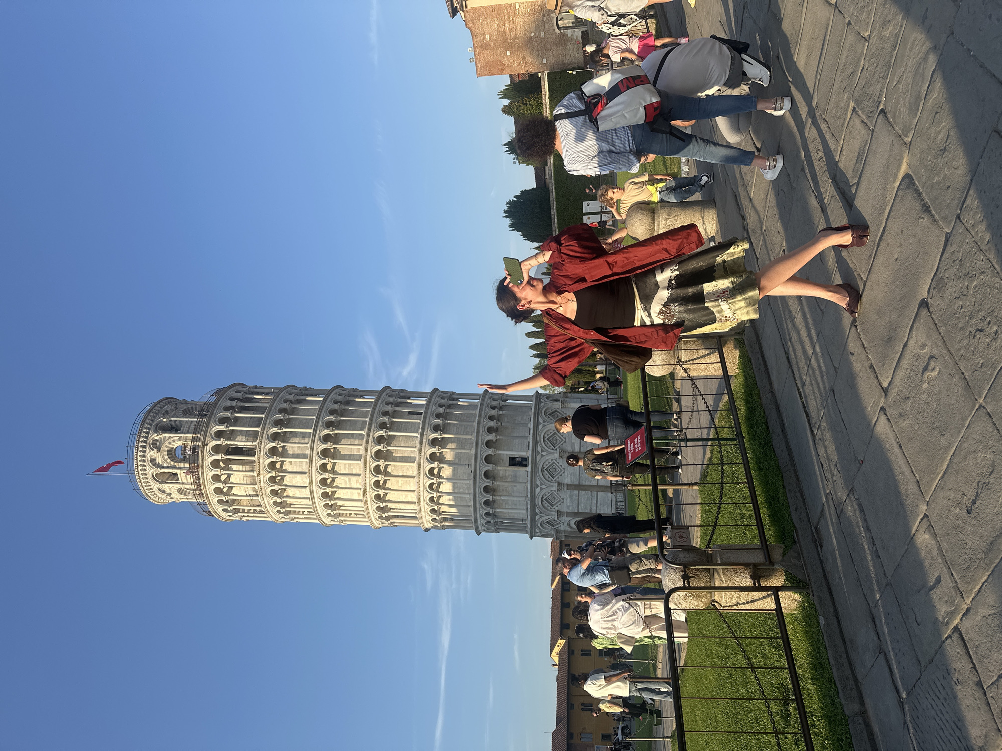 Tourists gather at Leaning Tower of Pisa during sunny afternoon