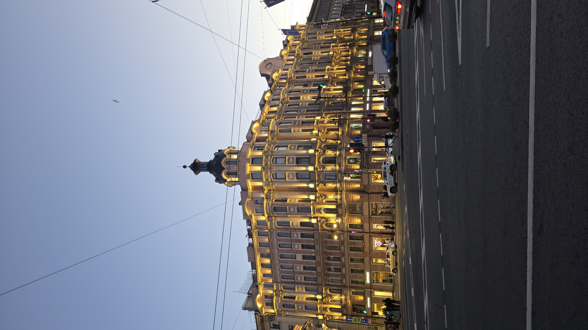Ornate urban street glows at dusk, buildings lit and sky fading