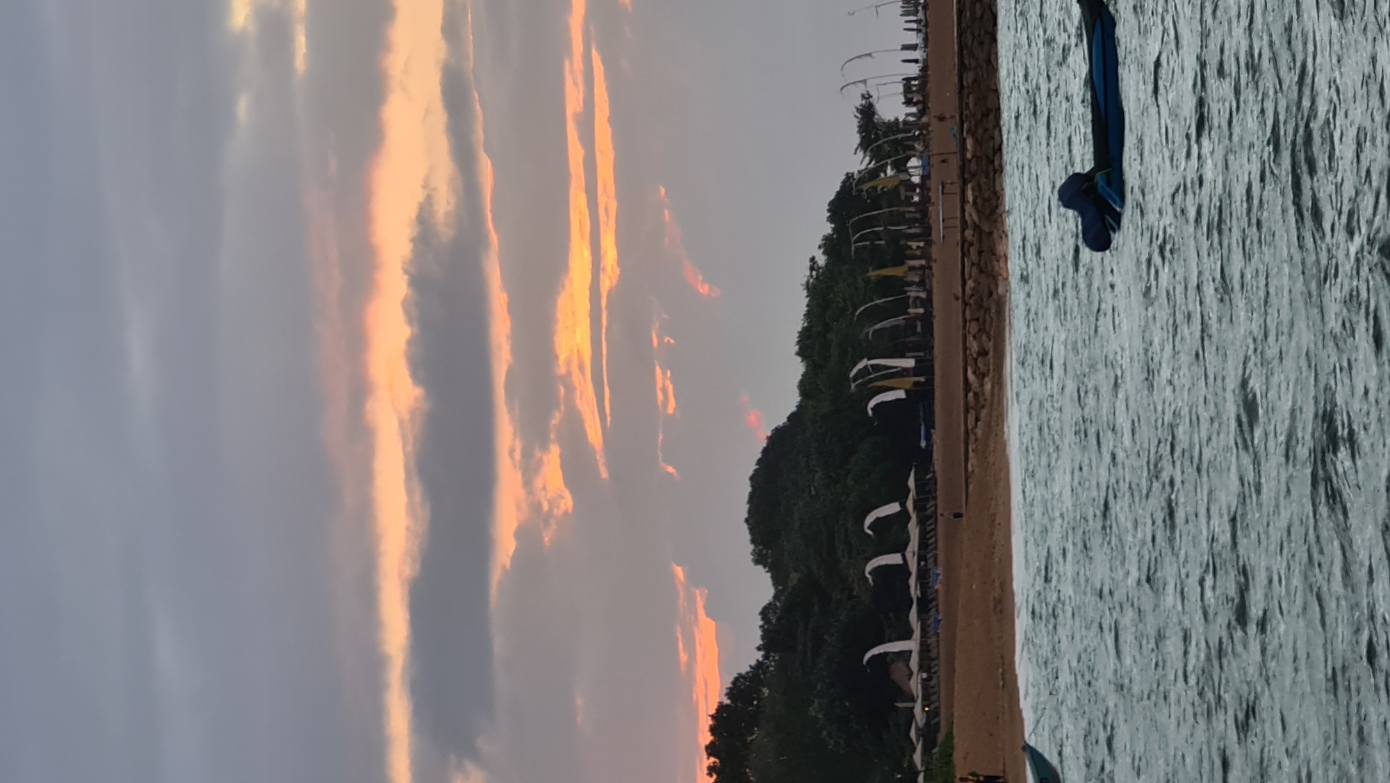 Bali waterfront at dusk, boats moored under a dramatic sunset sky