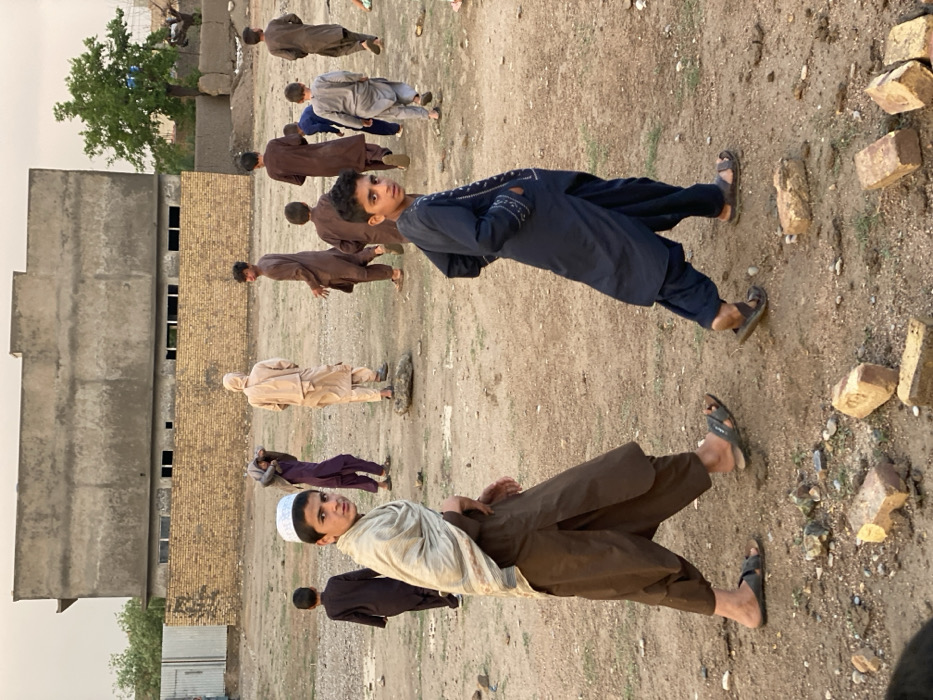 Children play amid construction, rain in Kandahar afternoon