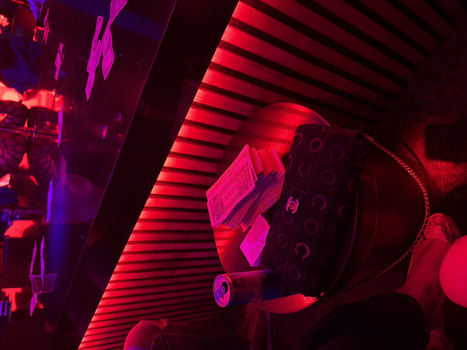 Red-lit table scene with cash, purse observed in West Hollywood