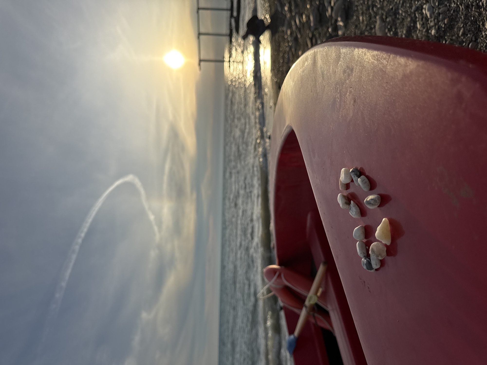 Golden hour on Sochi's pebble beach, red boat and all