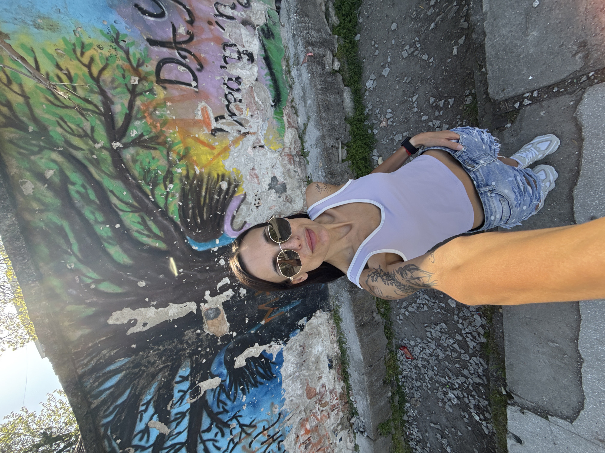 Woman takes outdoor selfies near graffiti wall in Bulgaria