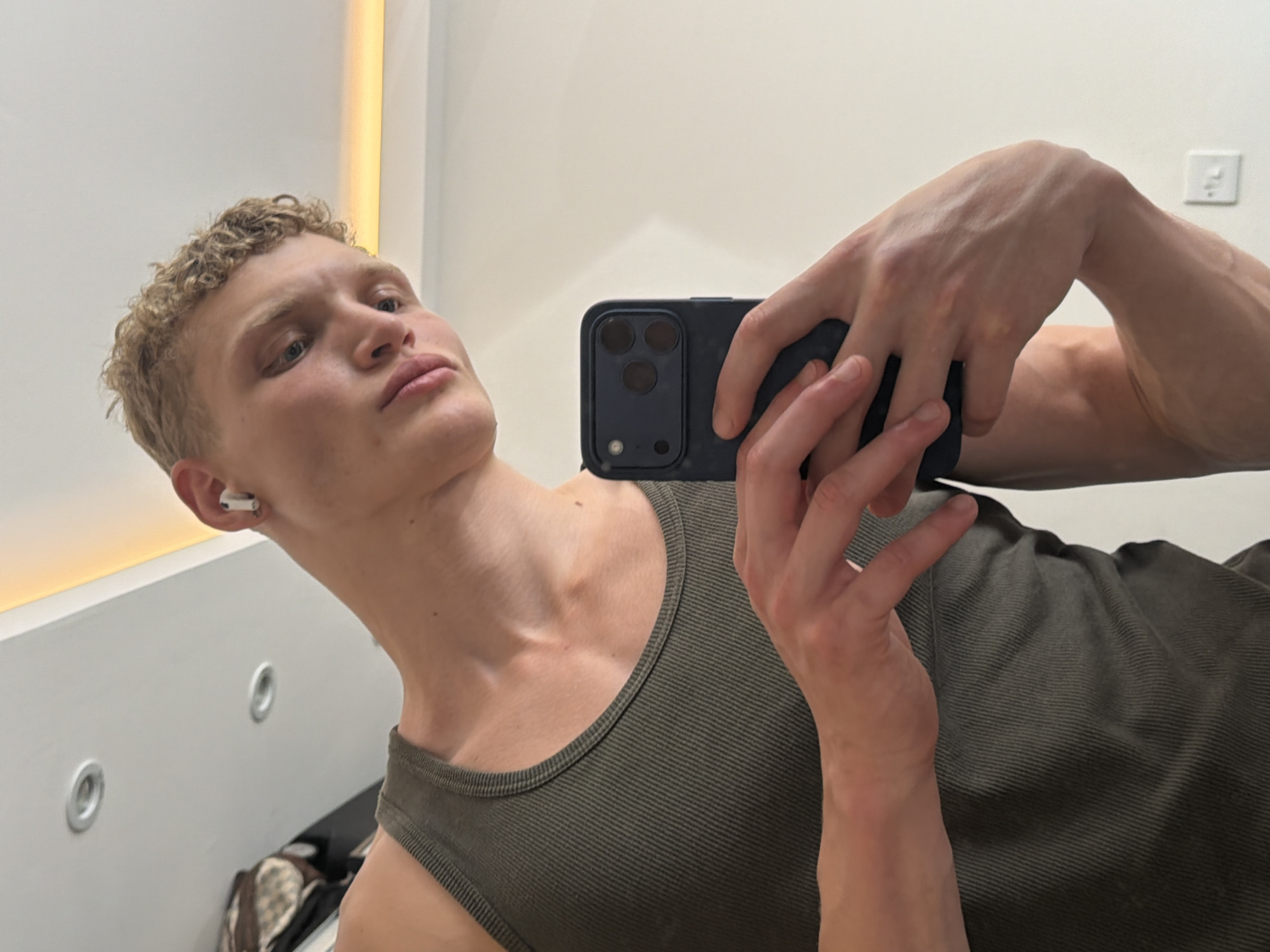 Mirror selfie in a London changing room, green ribbed tank top.