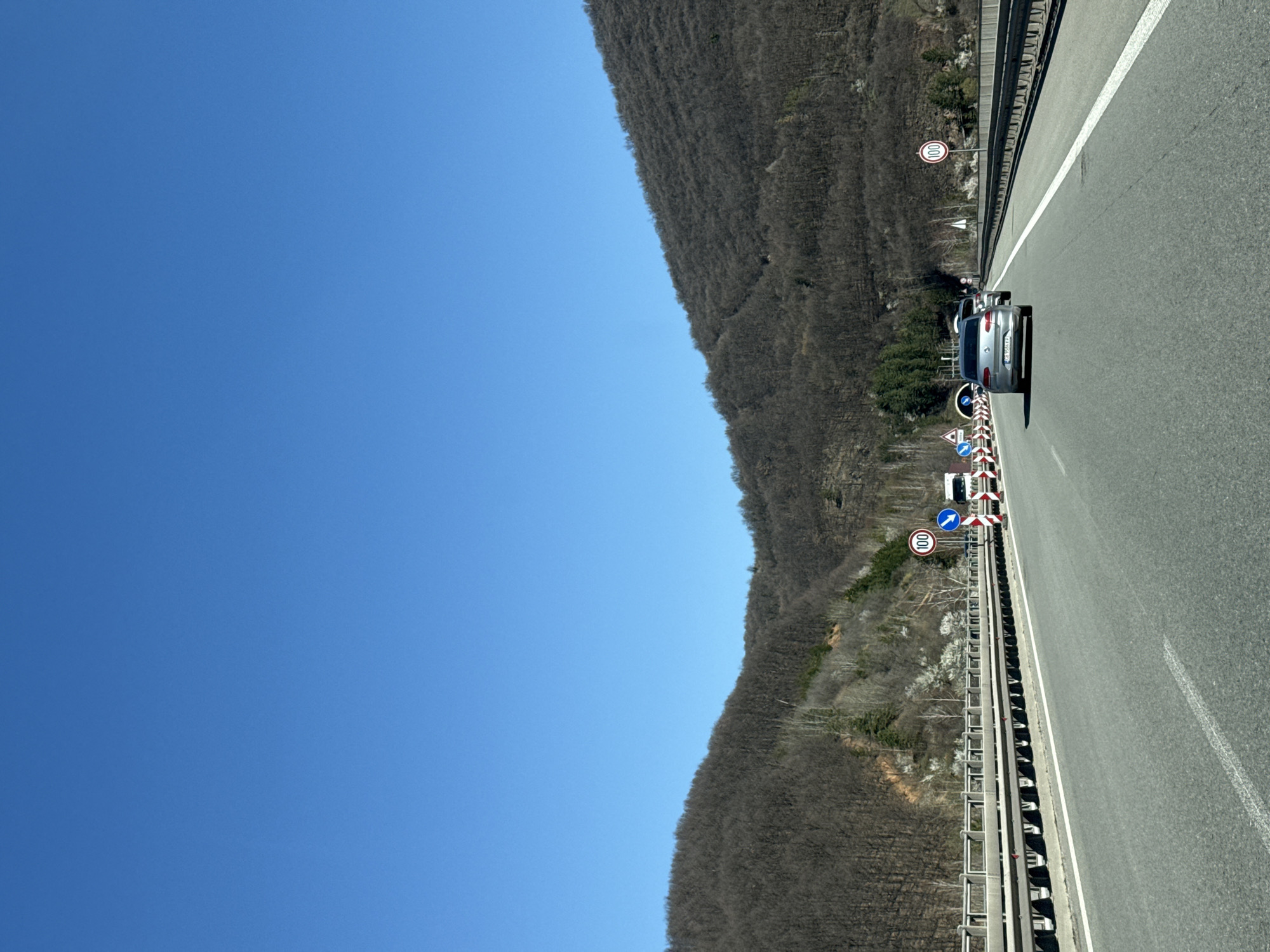 Silver car travels highway in Vrachesh amid construction signs