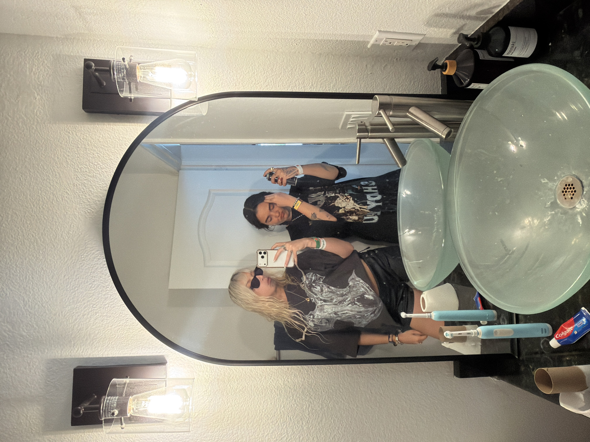 Two people take bathroom mirror selfies in Palm Desert