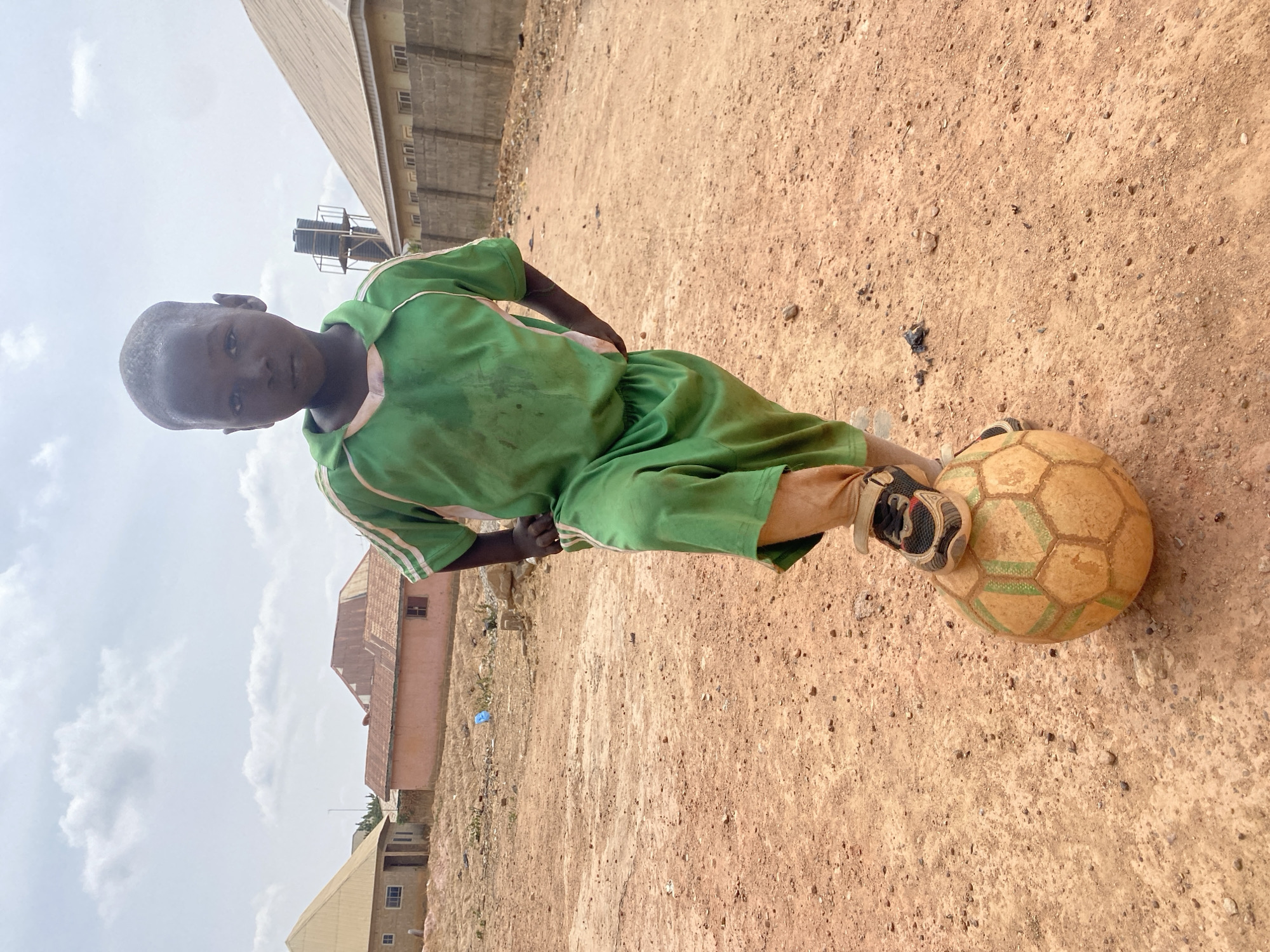 Young boy stands in dirt area in Rido, Nigeria