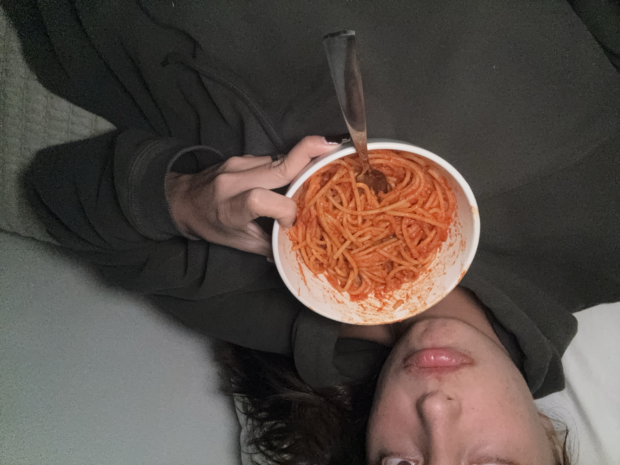 Person eats spaghetti while lying down in Acapulco bedroom