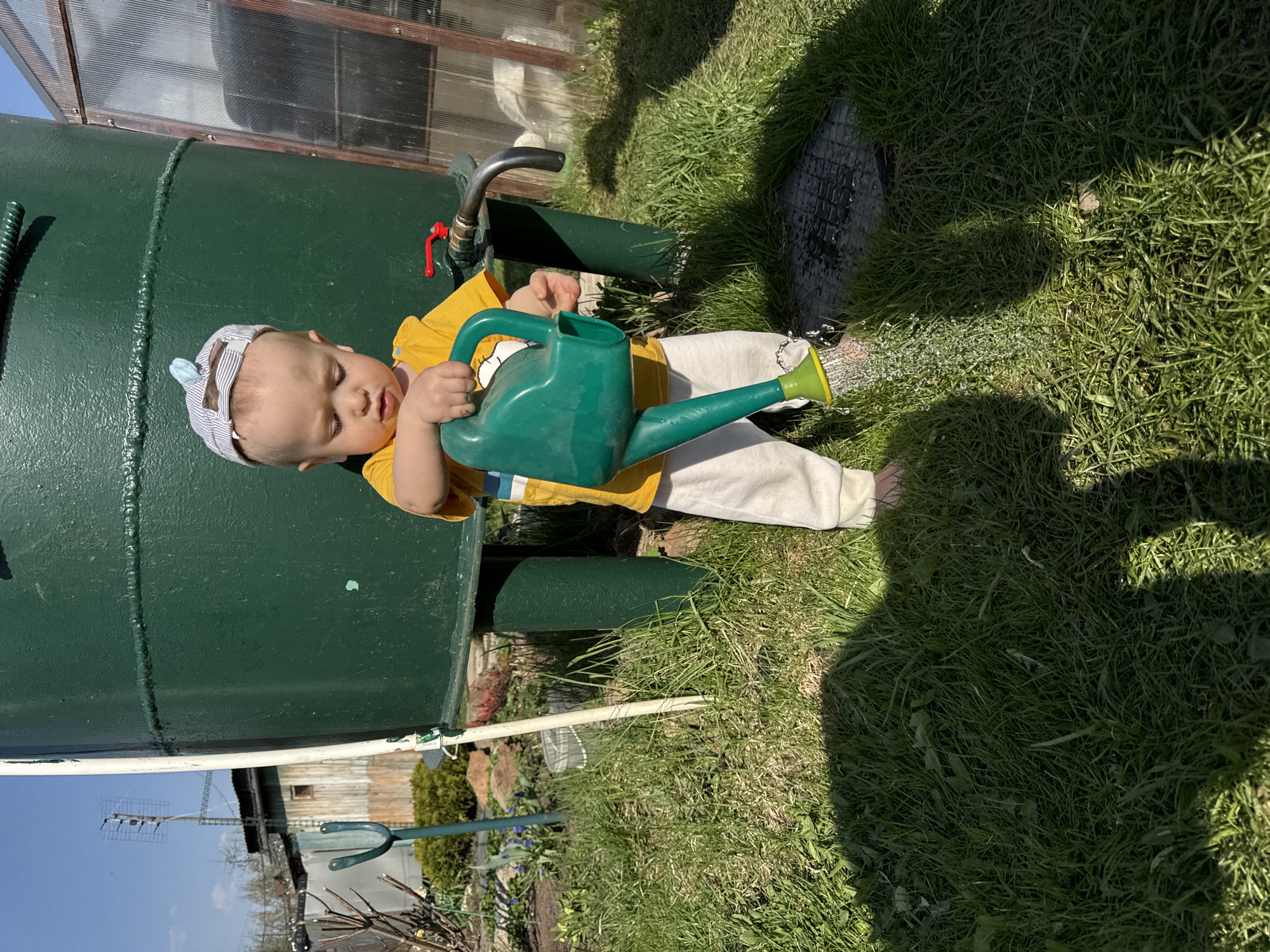Baby with watering can observed near green tank in Noviy