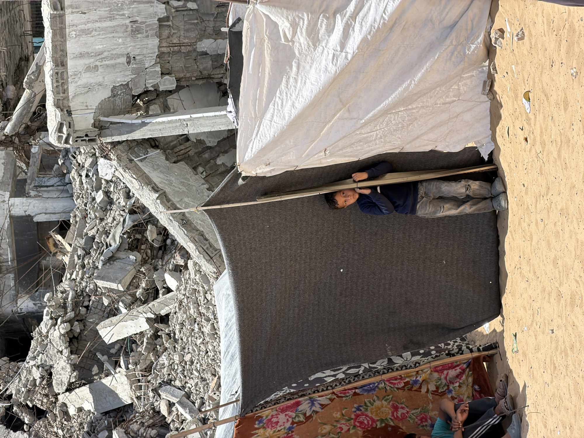 Gaza displacement: temporary shelters amid building destruction documented