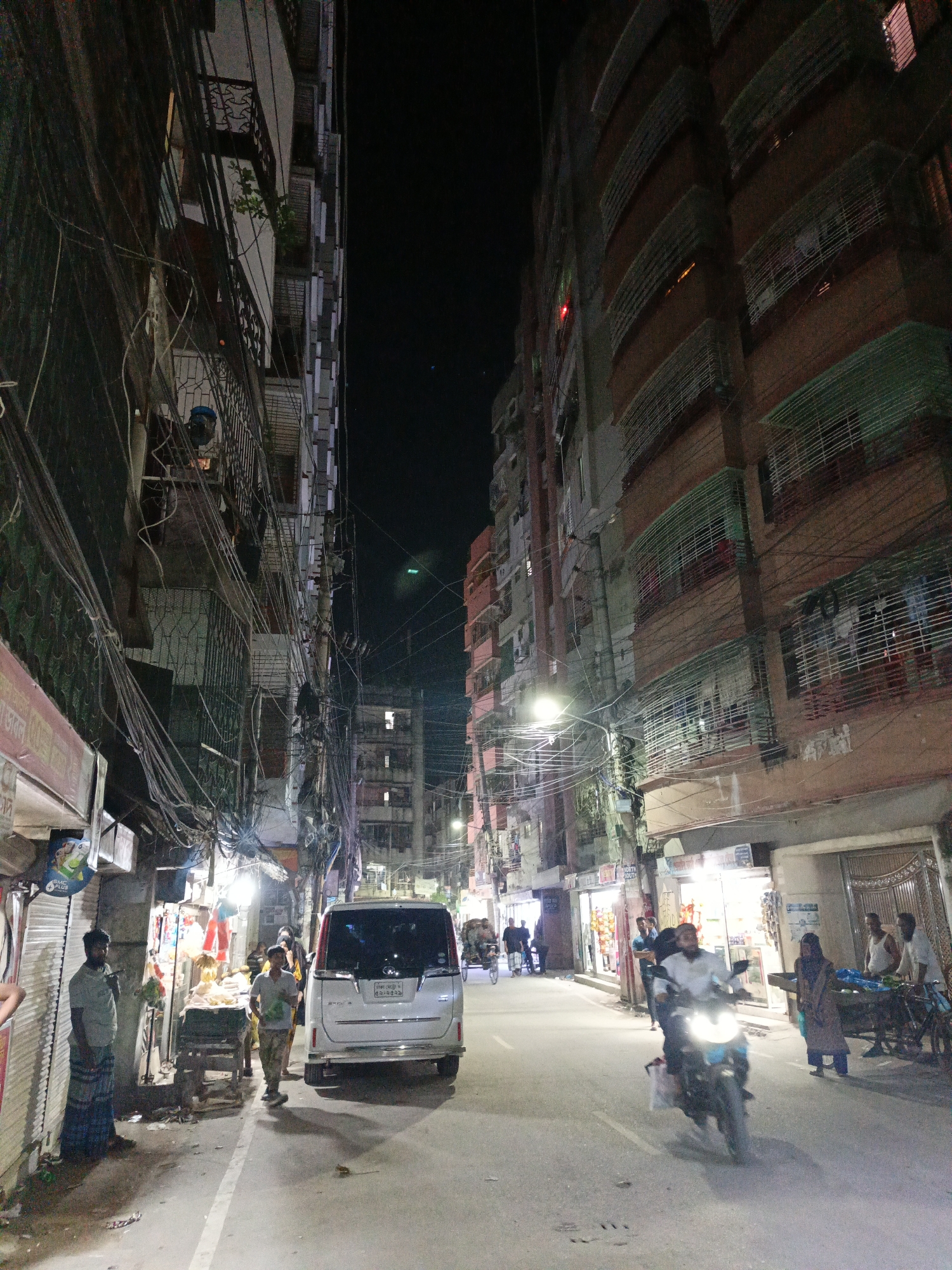Silver minivan blocks street at night under power lines