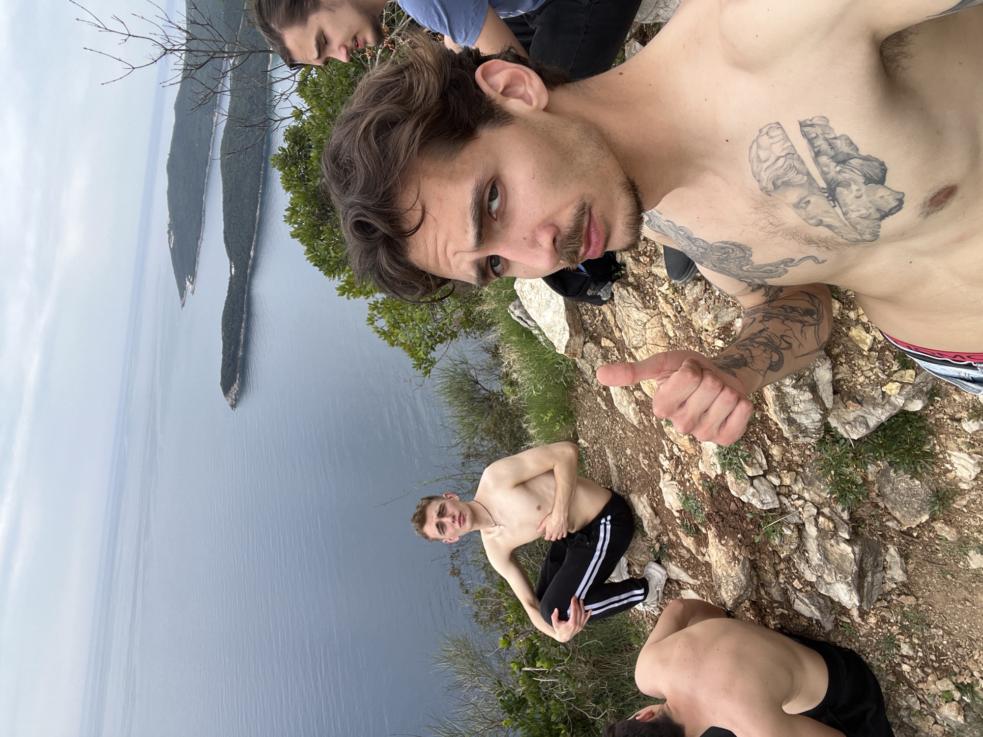 Four tourists pose on rocky cliff near Sveti Stefan