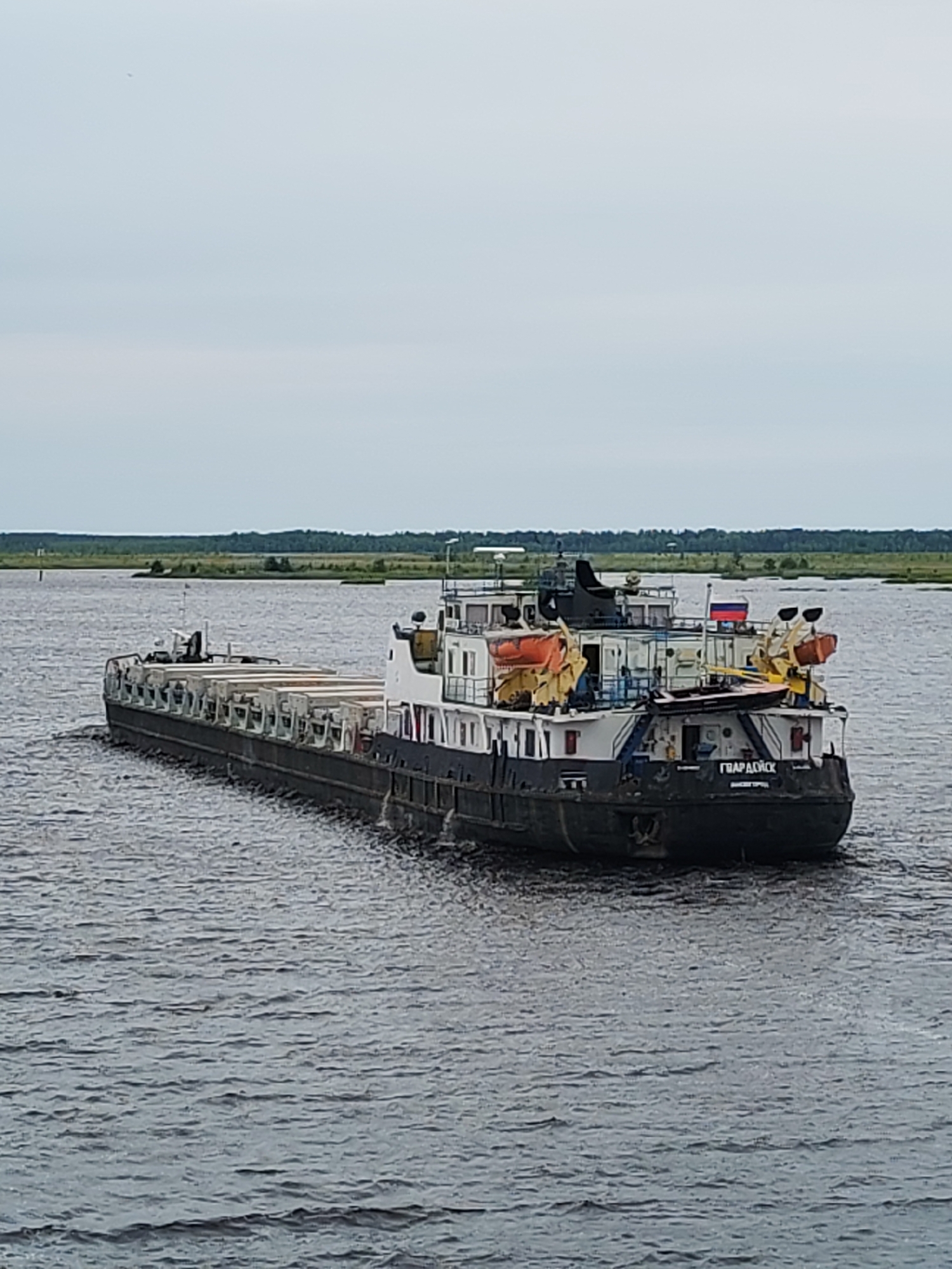 Ferry ride past cargo barge ГВАРДЕЙСК on a Russian river