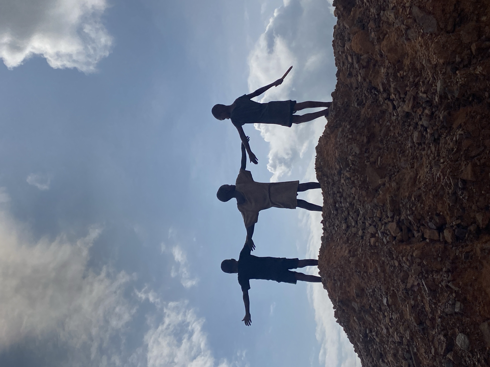 Kids on rocky ridgeline, eroded cliffs and green hills in Achara