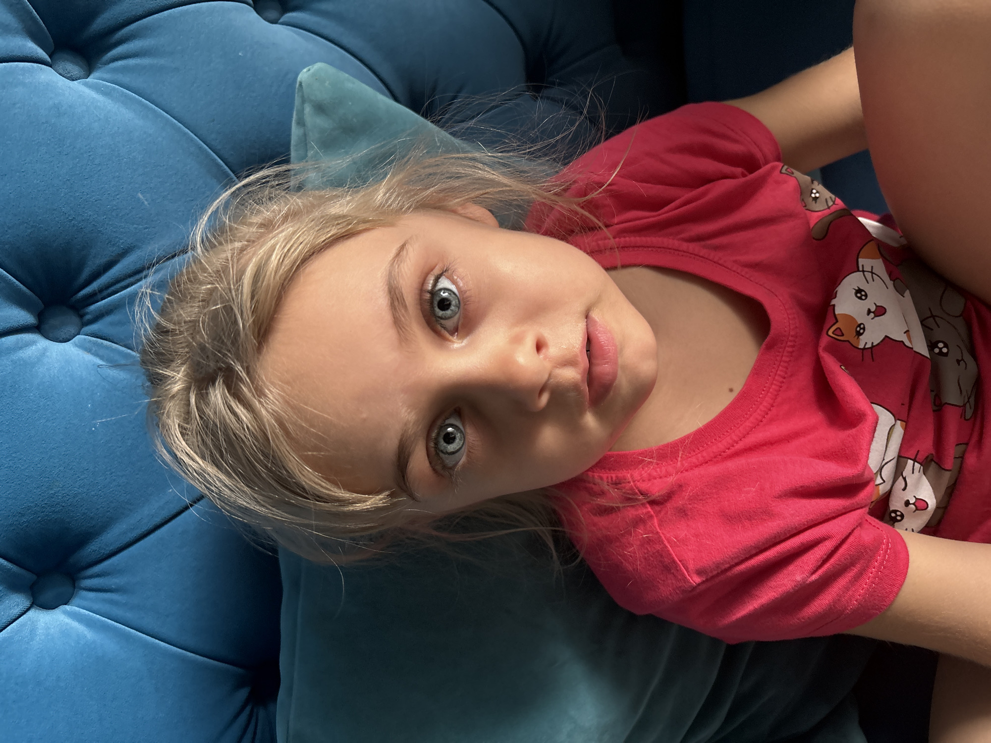Young girl rests on blue cushioned furniture