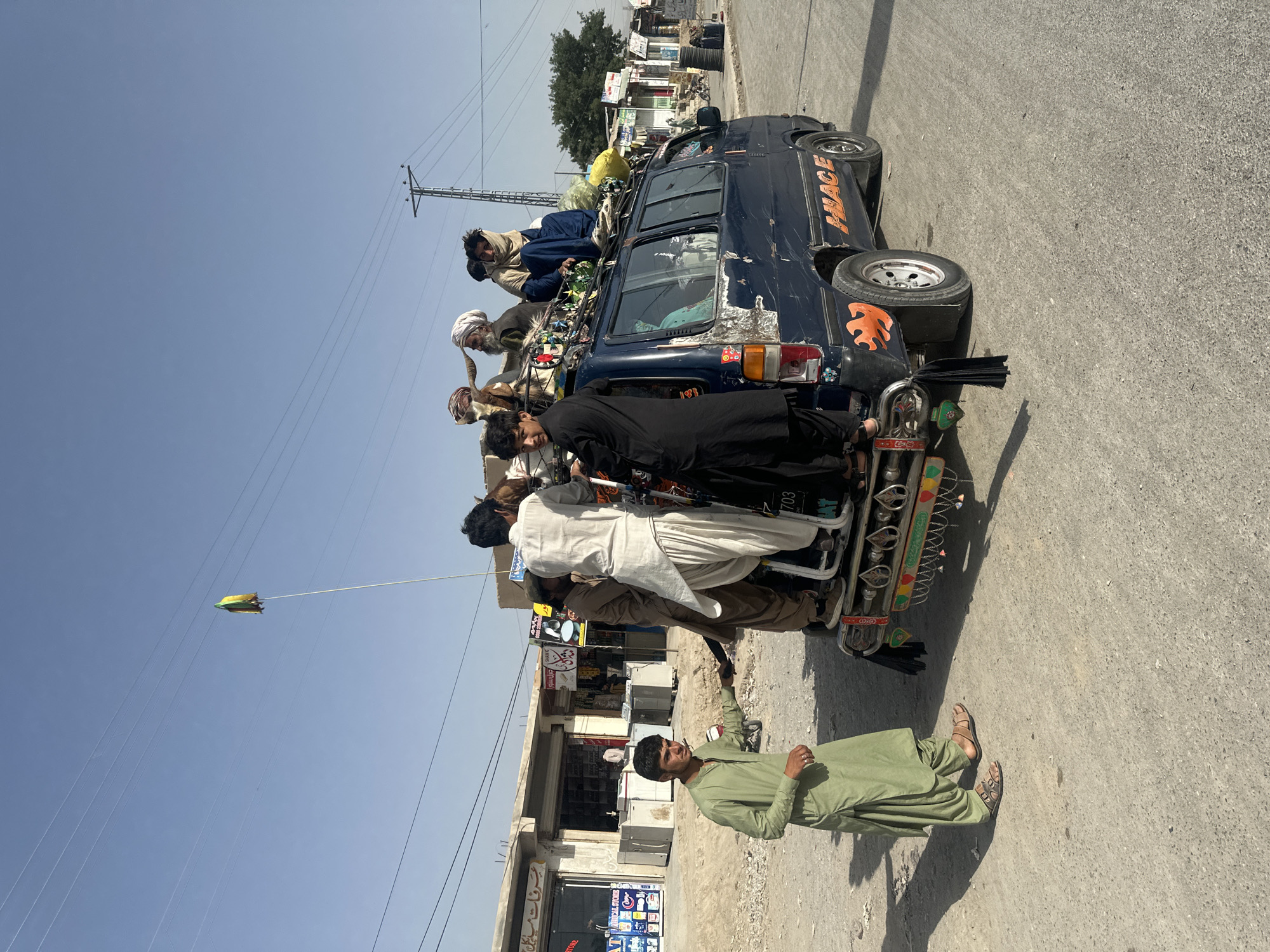 Overloaded decorated van carries passengers on roof in Quetta