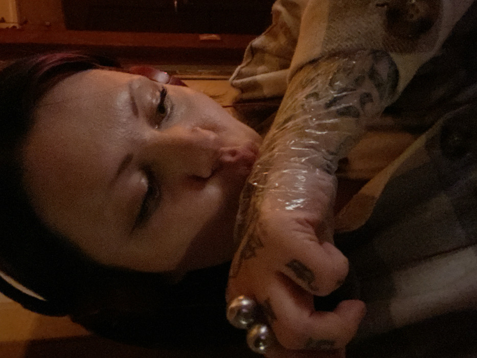 Tattooed woman with headphones rests in Kunje, Montenegro