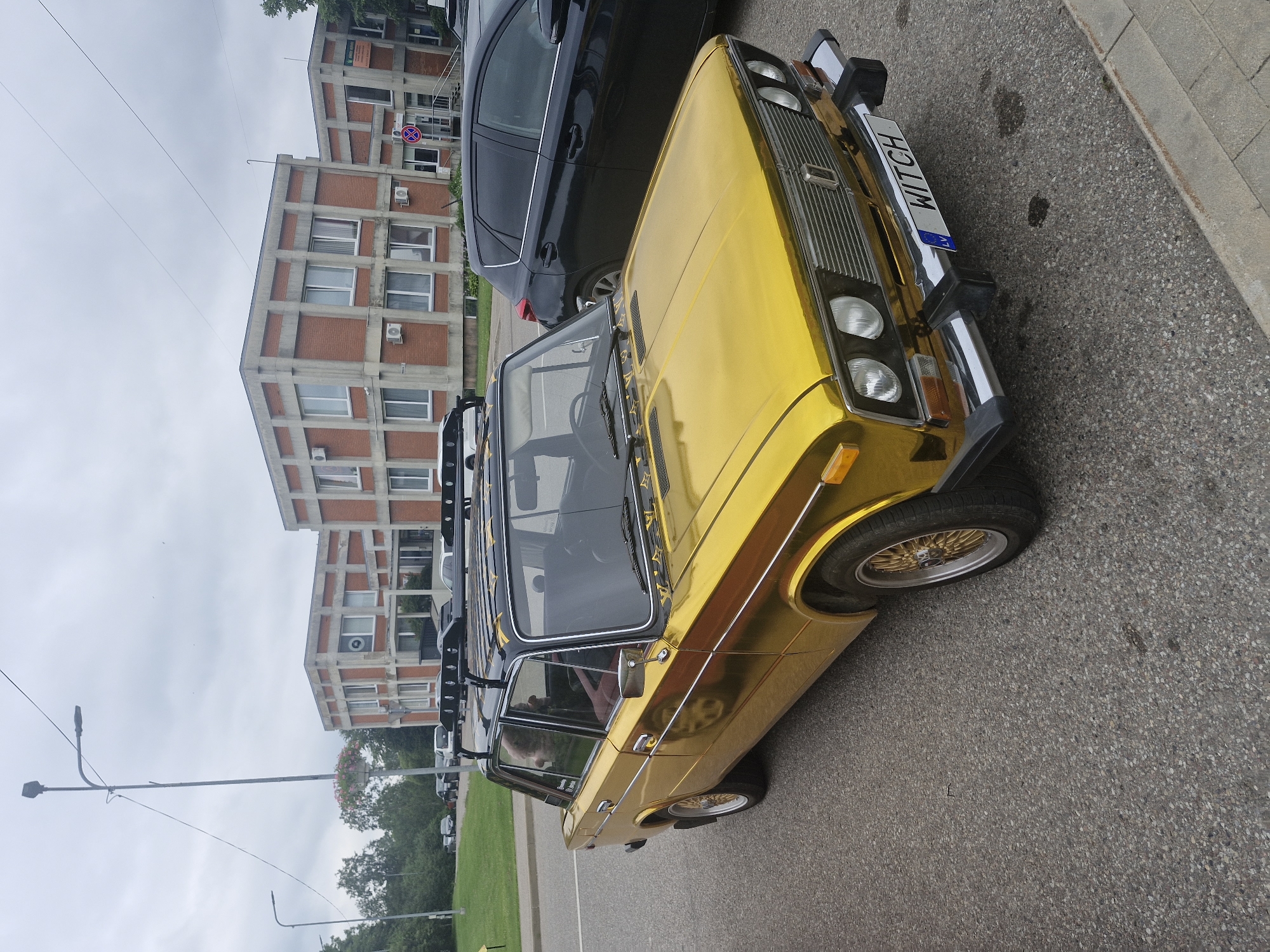 Chrome-wrapped Soviet sedan parked outside Brutalist buildings in Latvia