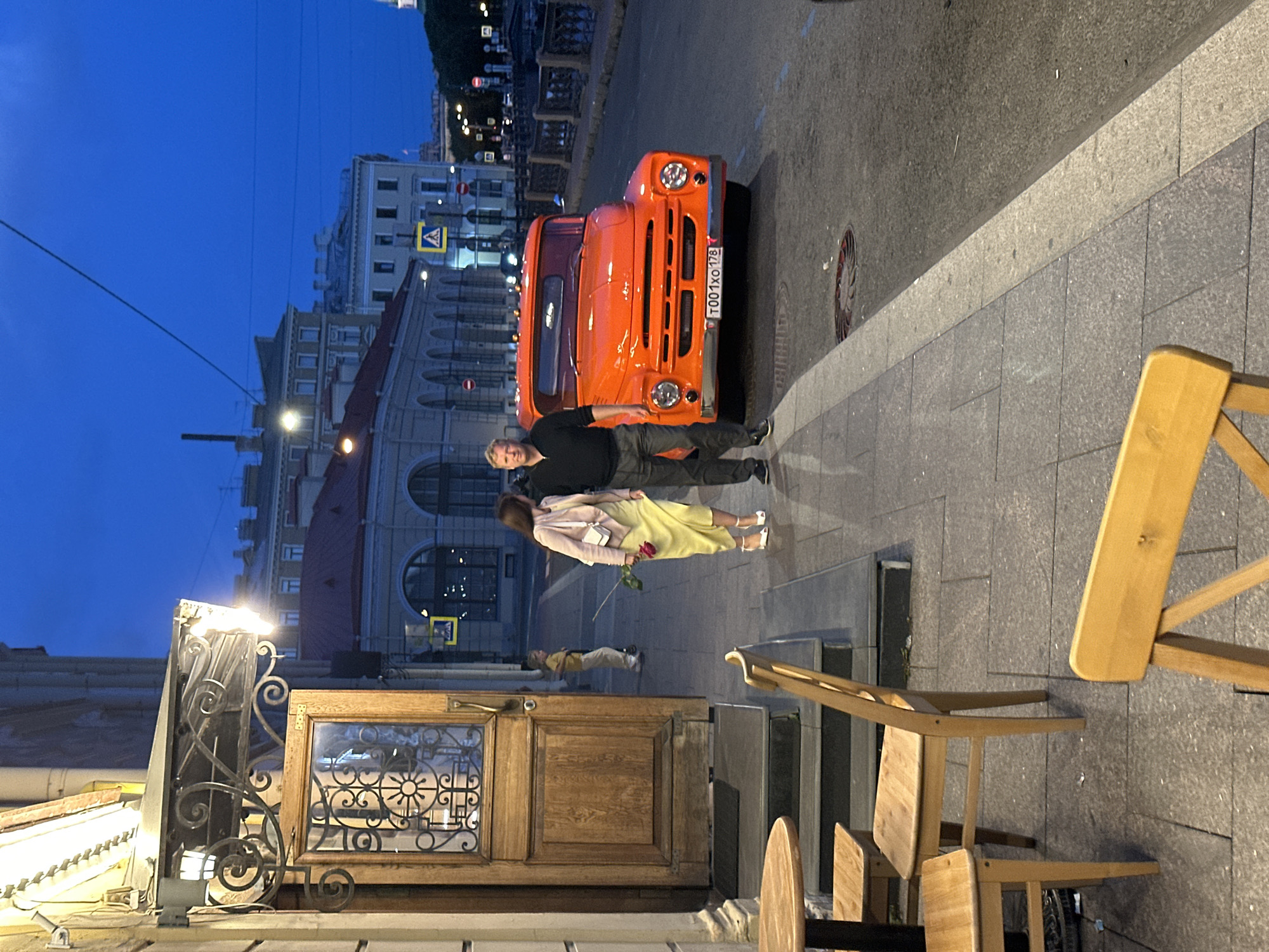 Vintage orange truck parked by a St. Petersburg canal at dusk