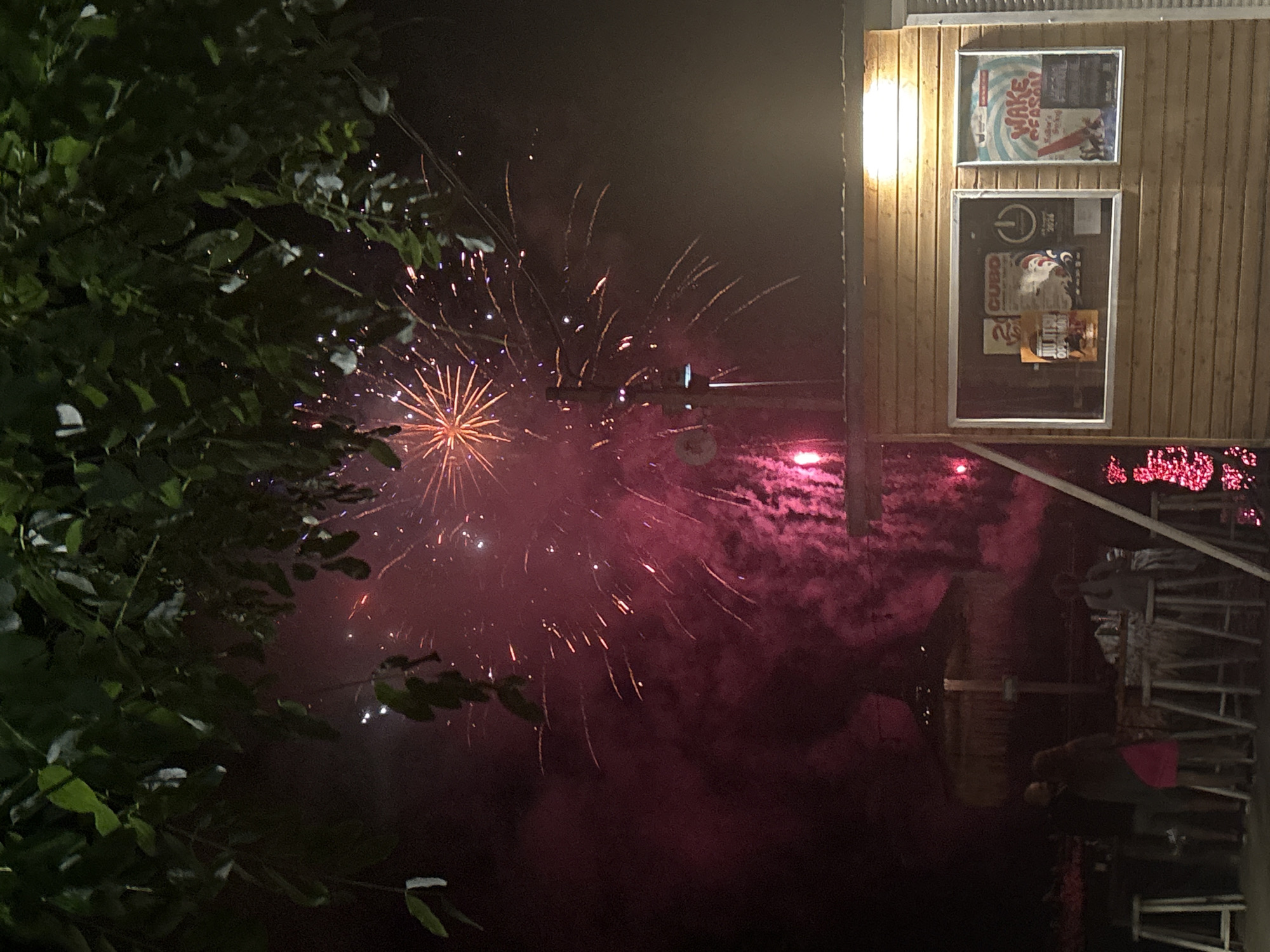 Fireworks light up the night sky above a small wooden building.
