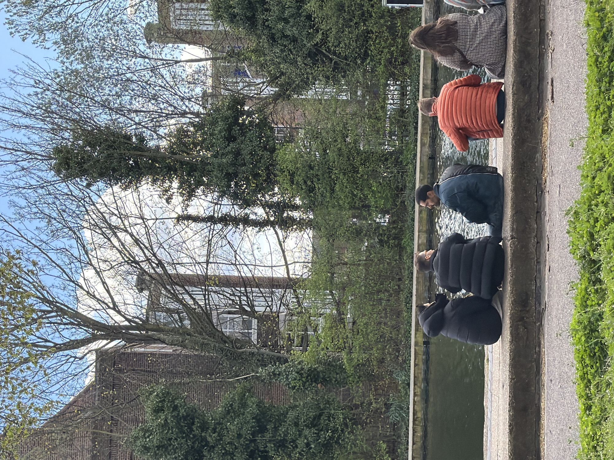 Four people sit by London canal in cool weather