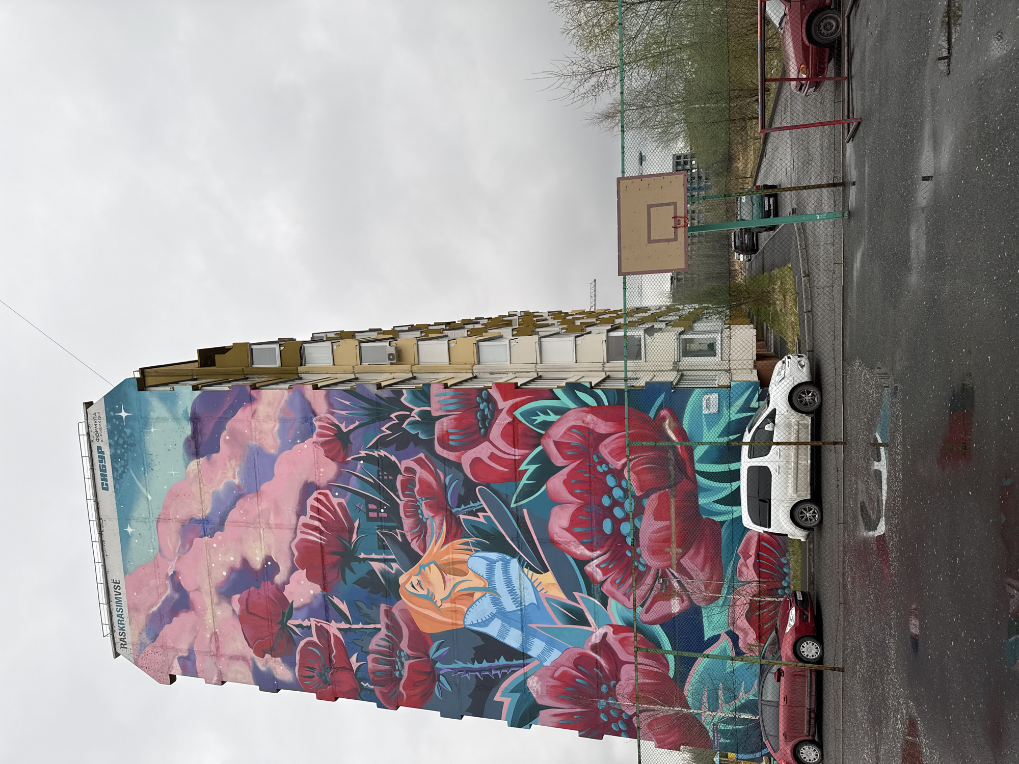 Child plays near floral mural on rainy day in Tobolsk