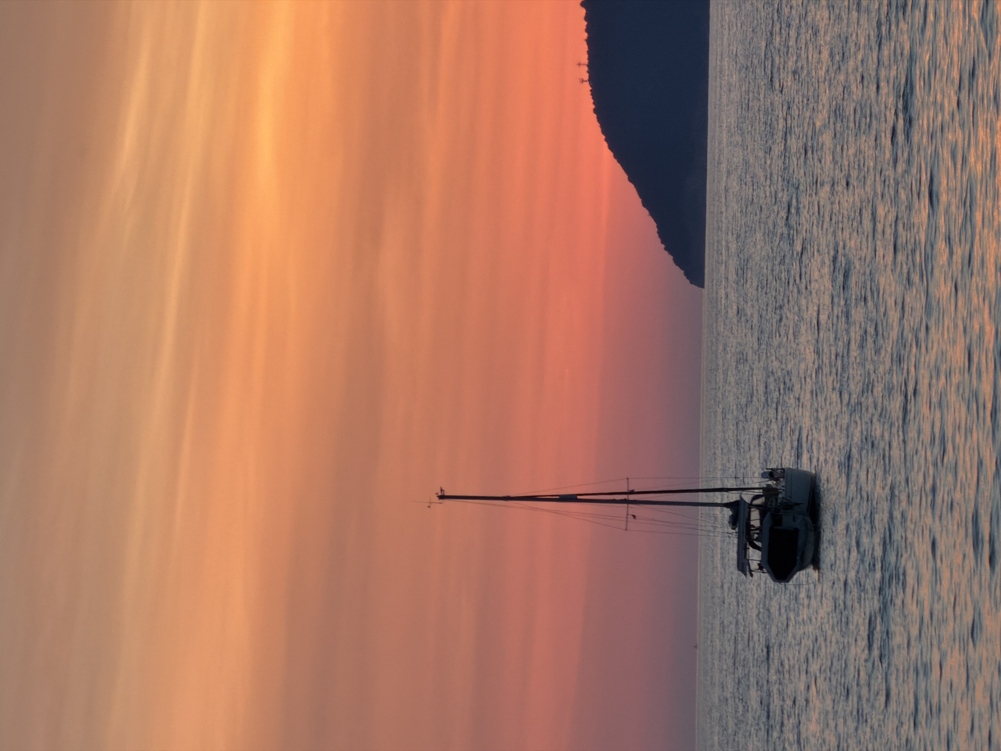 Golden hour on a Bar, Montenegro beach with a sailboat offshore.