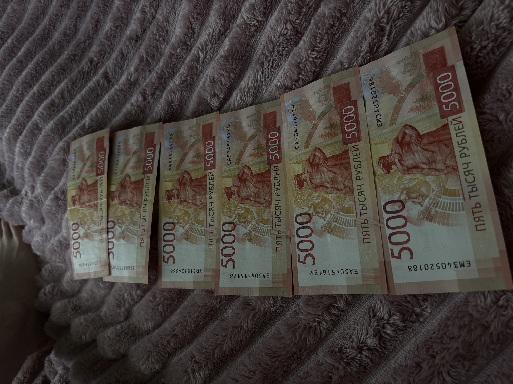 Person photographed with Russian currency and jewelry on blanket