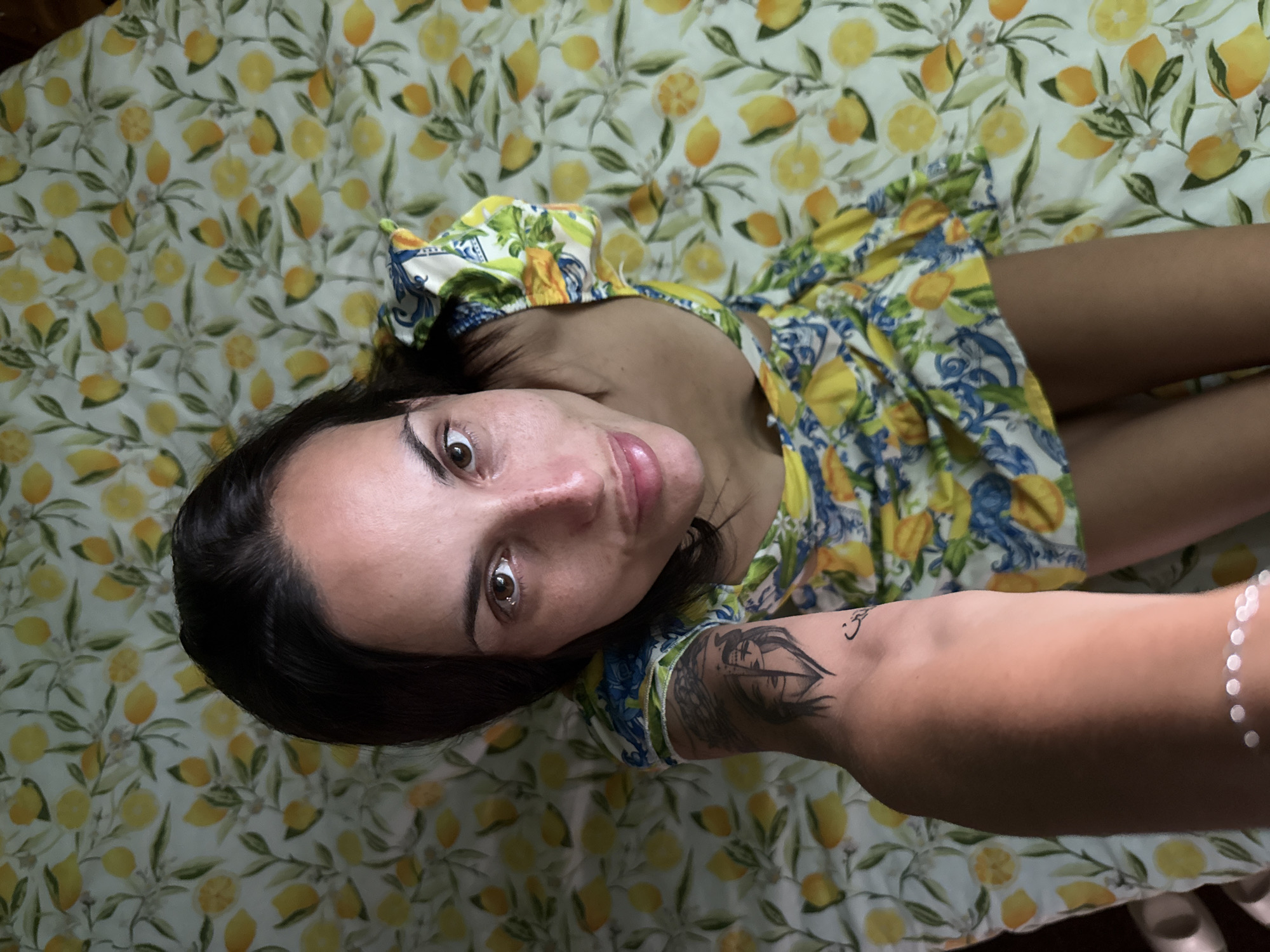 Woman photographed in lemon-print dress on matching sheets, Pleven