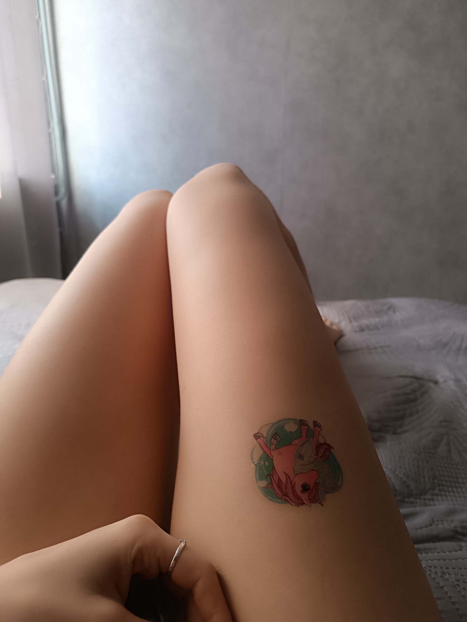 Person shows off pink unicorn temporary tattoo on bed