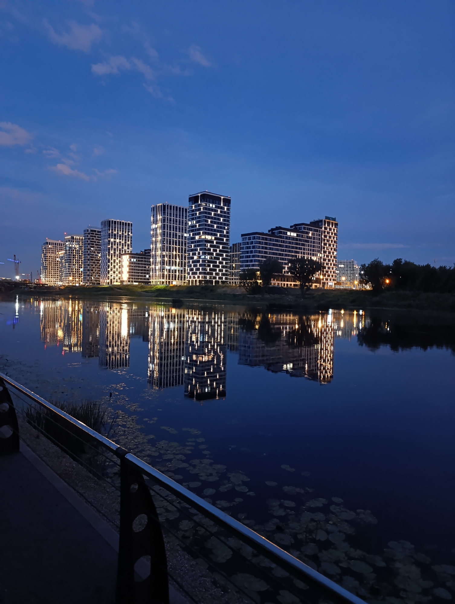 Moscow riverfront at dusk, lights hitting calm water
