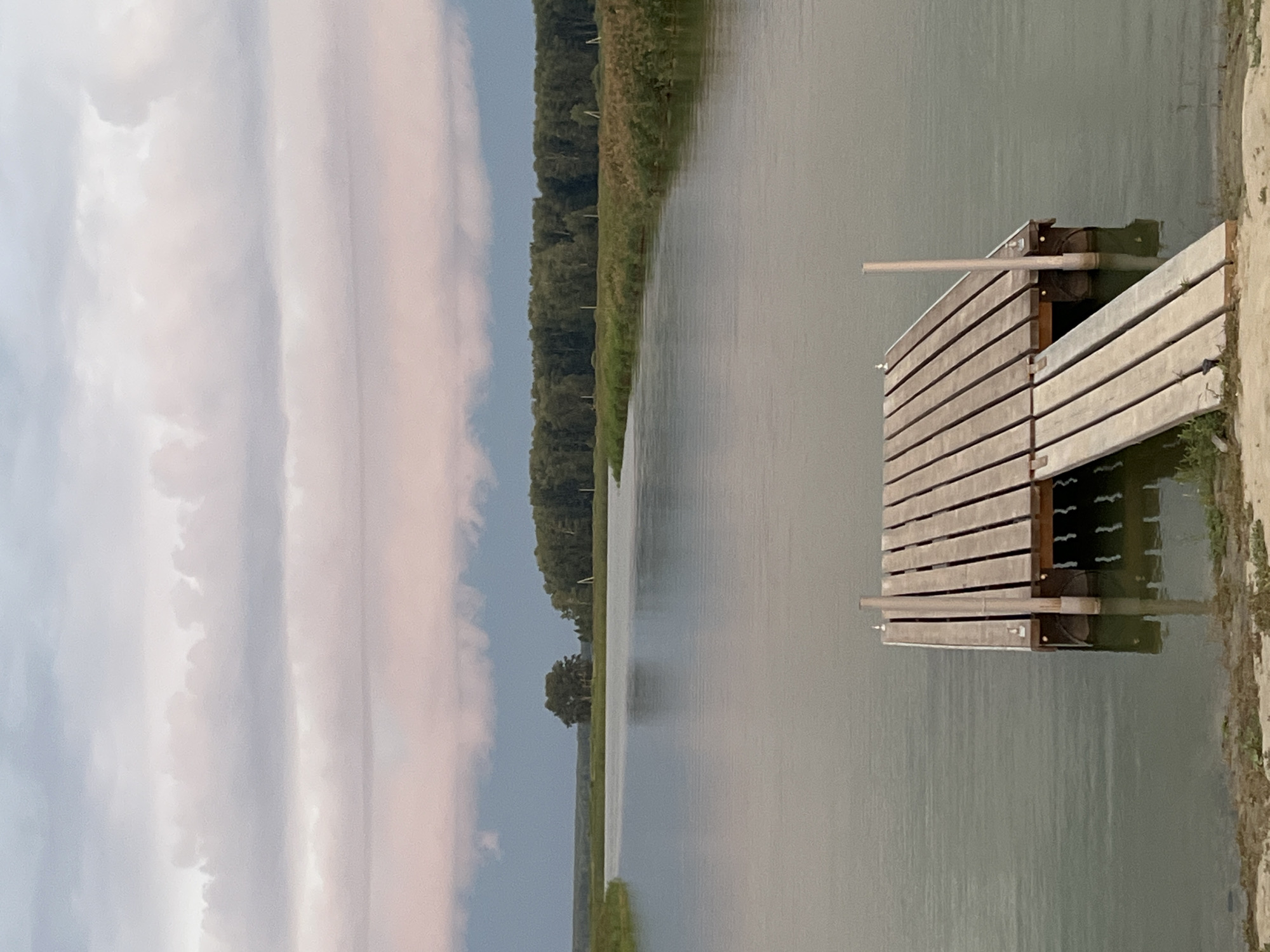 Calm water and a wooden pier under cloudy skies in Novopichugovo