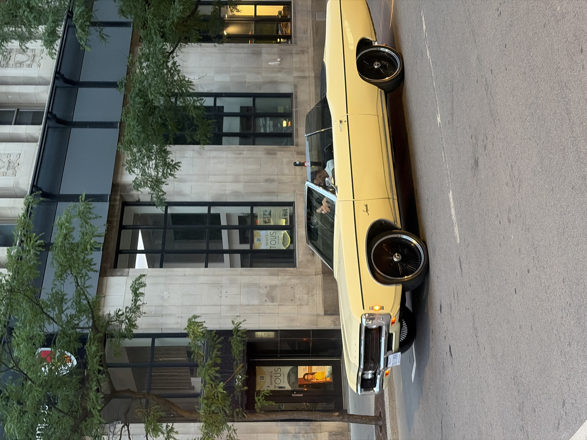 Vintage convertible drives through twilight Montreal streets
