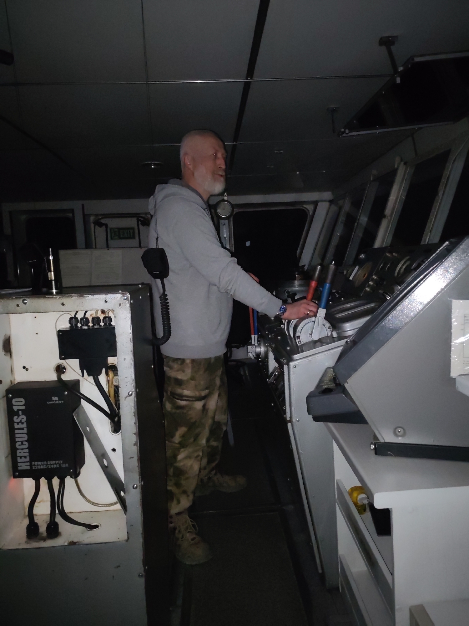 Man operates vessel bridge controls at night in Golyashi