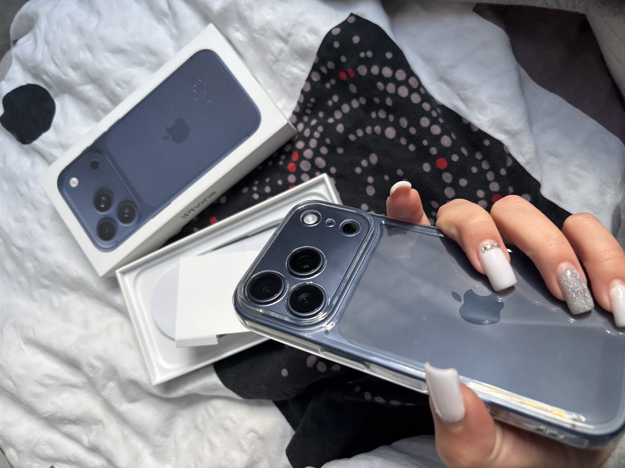 Person displays new blue iPhone with packaging in bedroom