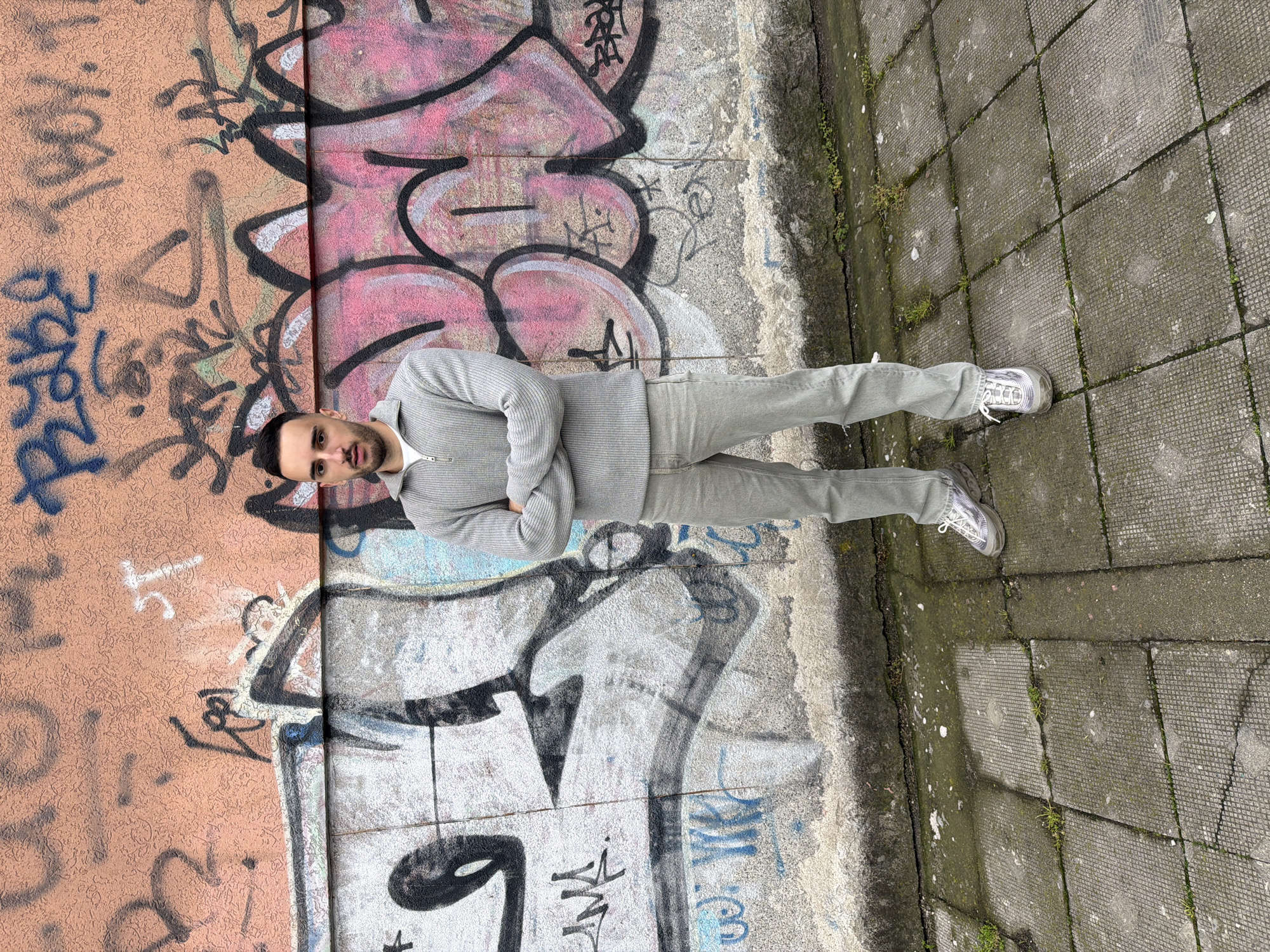 Young man poses for casual photos near graffiti in Plovdiv